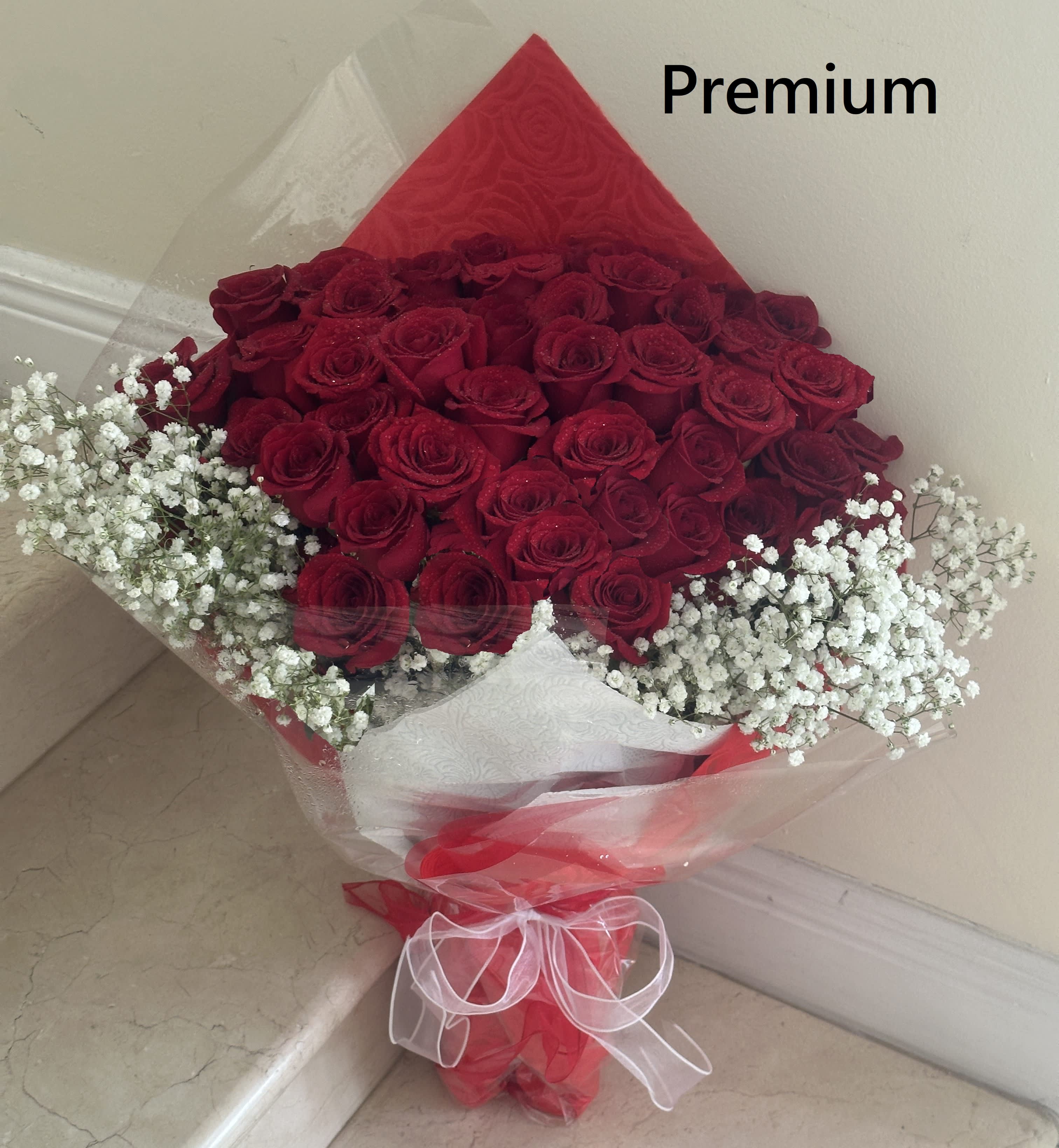 36 Long Stem Red Roses wrapped with Tissue and/or Cellophane paper with a Bow. - 36 Long Stem Red Roses wrapped with Tissue and/or Cellophane paper with a Bow. Beautifully arranged with a skirt of White Baby Breath and Greens.