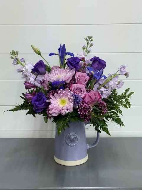 Butterfly &amp; Lavender Pitcher Bouquet - Beautiful assortment of lavender flowers such as roses, stock, buttons and waxflower together with purple iris, lisianthus, alstromeria and statice arranged in a lavender ceramic pitcher.   Flowers and colors may vary depending on availability. Local delivery ONLY. (other shops may not carry same container)  Pitcher size: 6''H x 7''W (from tip to end of handle)