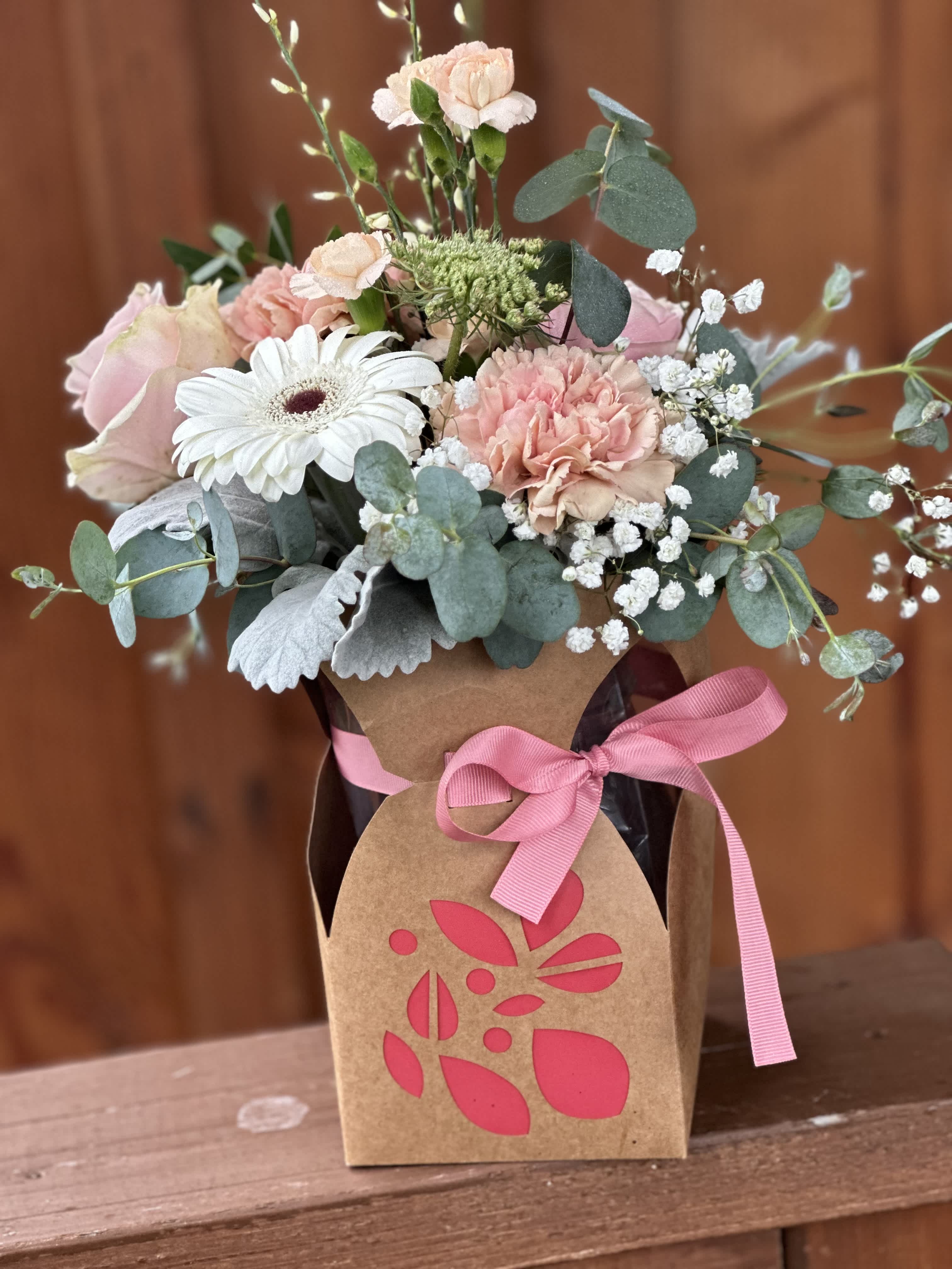 Paper vase bouquet  - Beautifully arranged roses, natural carnations , gerber daisies and mini carnations  tucked into a decorative paper bag wrapped vase . Flower colors may vary based on availability . 