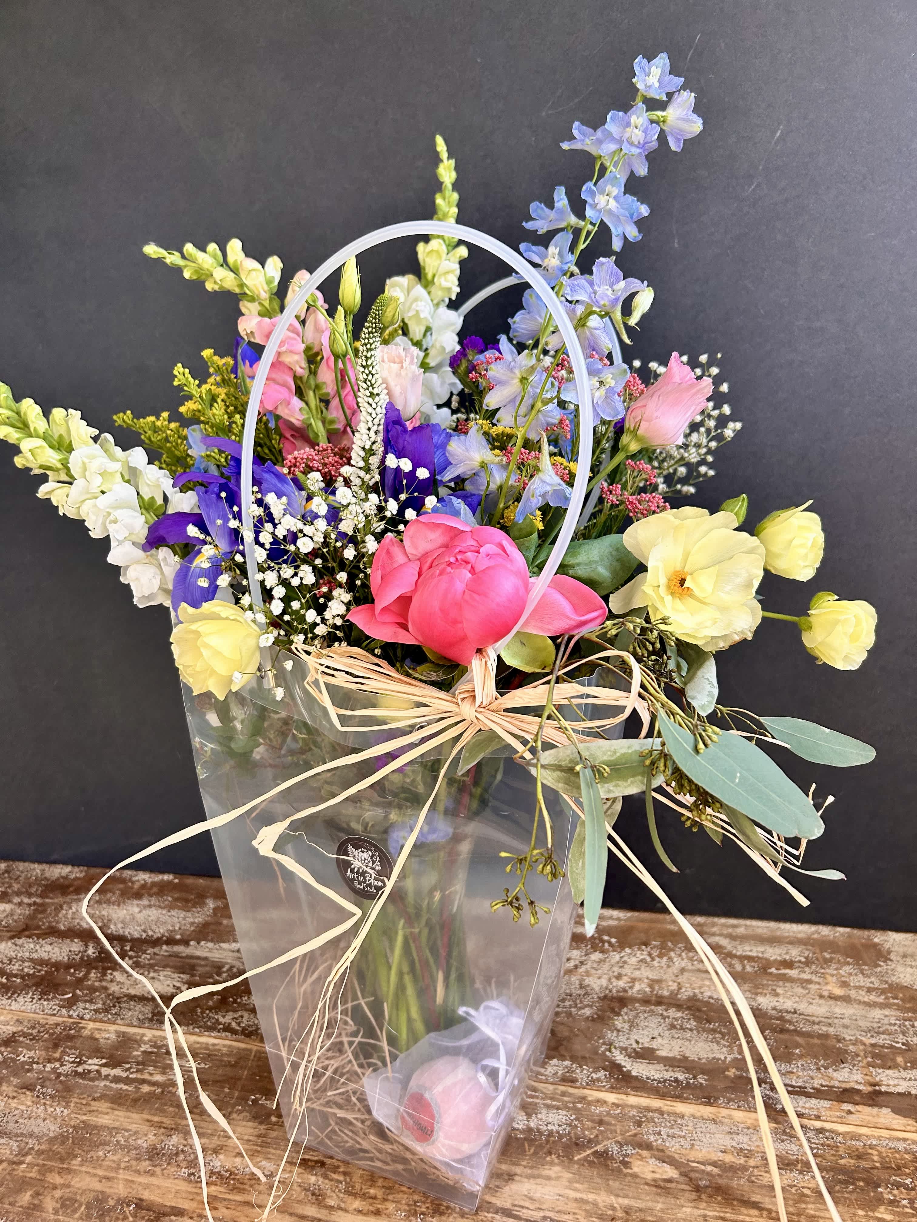 Mother's Day Special - A tote bag with an assortment of fresh blooms in a vase and a bath bomb (fragrances will vary) could make a perfect start to someone's Mother's Day! The design is roughly 2' tall. The deluxe version will have two bath bombs and more blooms.
