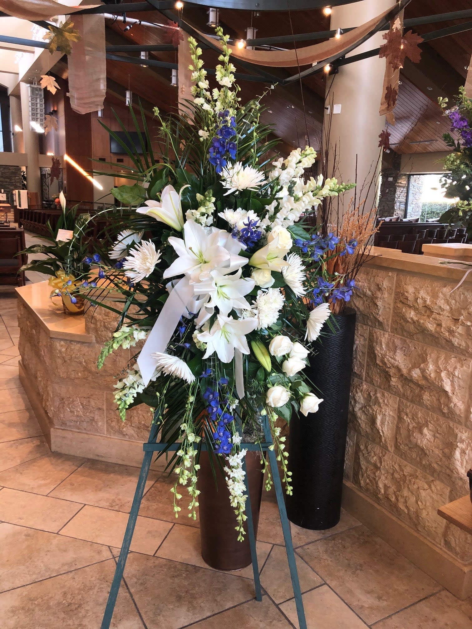 White and Blue Sympathy Standing Spray Piece White and Blue Sympathy Standing Spray Piece - MUST BE ORDERED TWO DAYS IN ADVANCE. White and Blue Sympathy Standing Spray Piece. Types of Flowers: White Asiatic Lilies, Blue Delphinium, White Larkspur, White Snapdragons, White Asiatic Lilies, White Roses and White Spider Mums on an easel. Availability: All year round Substitute Available: Yes Design View: Front Facing View Photo shown: Regular