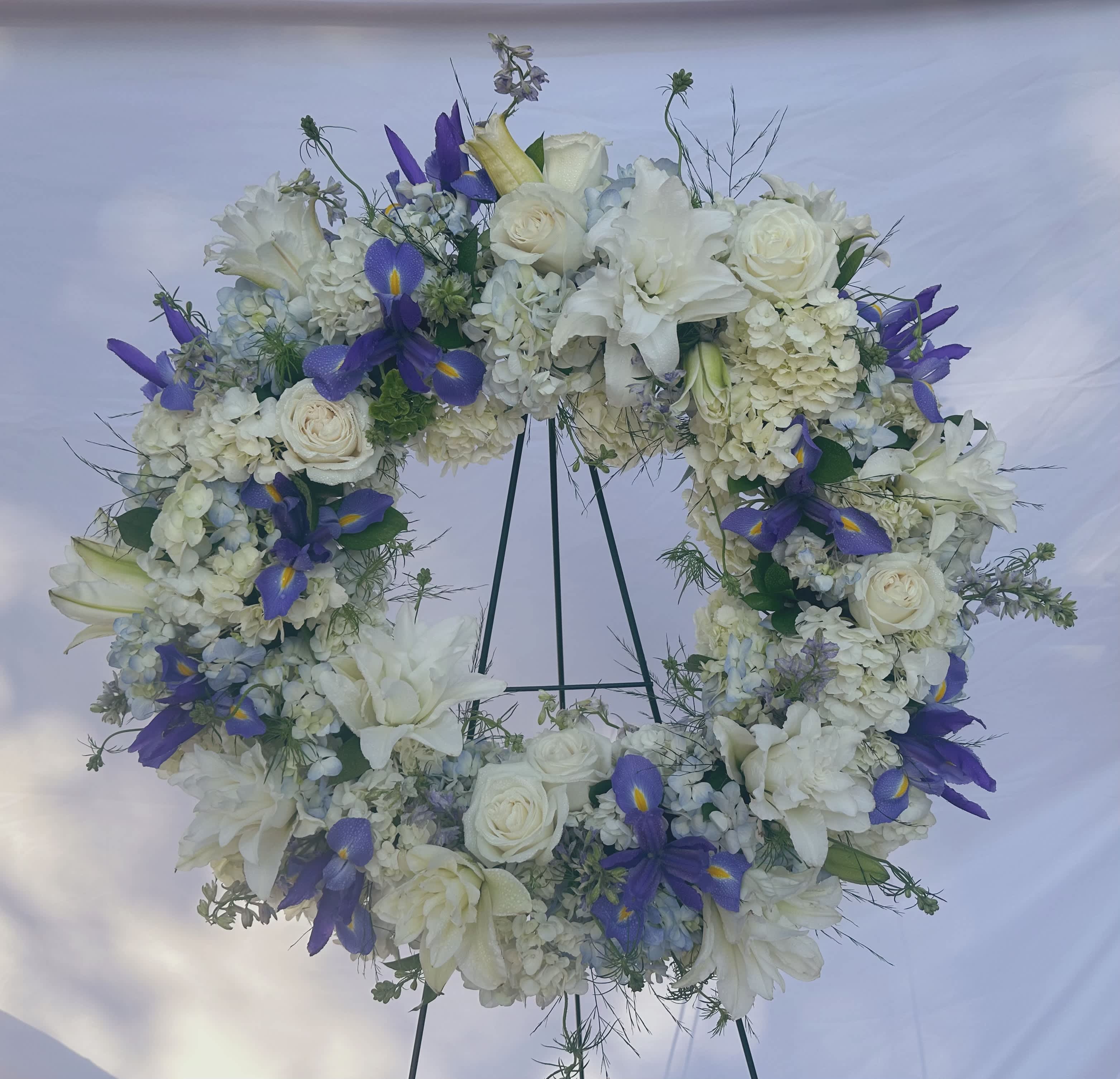 Blue &amp; White Sympathy Wreath  - Large funeral wreath on a stand: Includes: Hydrangeas, roses, lilies, iris, larkspur &amp; more beautiful flowers and foliage. Show at standard - Deluxe and premium will be fuller larger thank pictures with added flowers to value. 