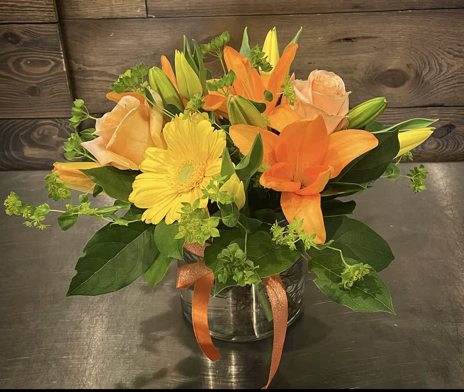 Sunny Siesta Sunny Siesta - A bright mix of yellow and orange flowers, including asiatic lilies, gerbera daisies and roses an uplifting bouquet for any day.  Approx. 10" Tall x 9" Wide