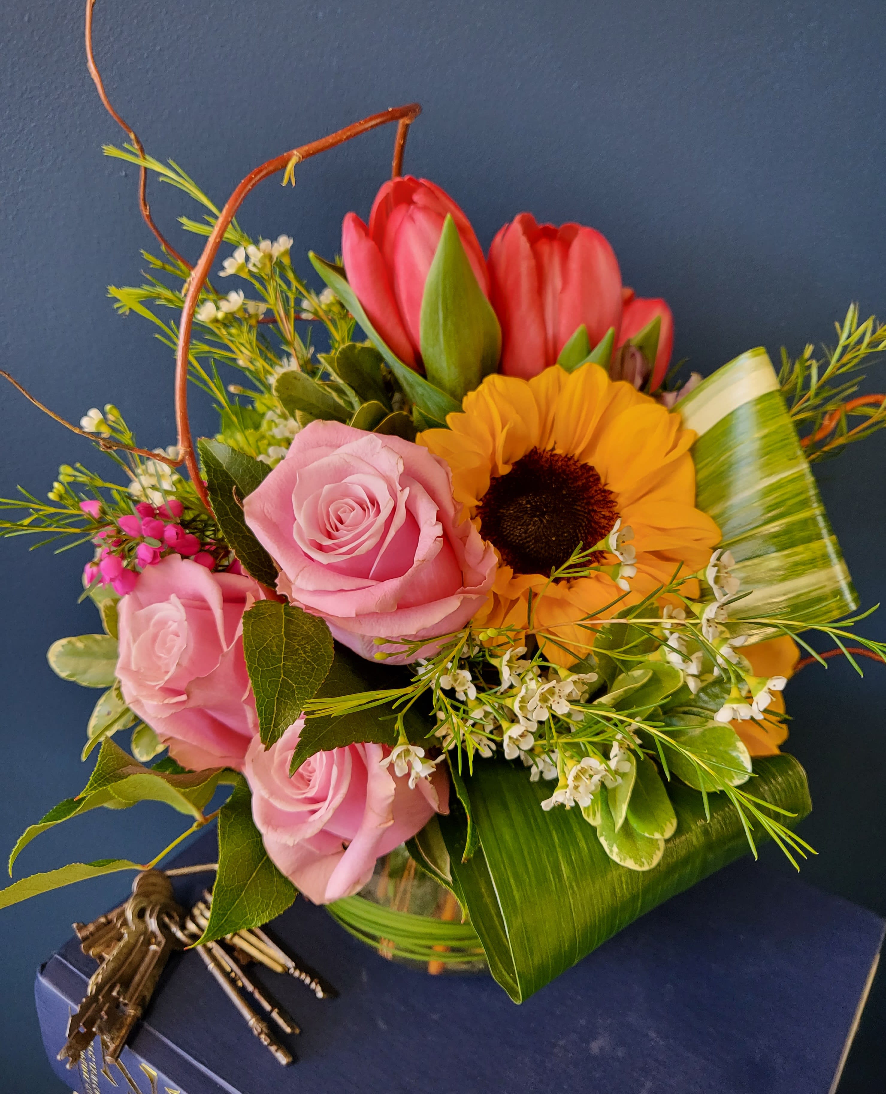 April - This arrangement features the best &amp; most popular flowers of spring blended together in a bubble bowl. This is the perfect arrangement for the season to add to any table, counter, or desk.  Sunflowers, tulips, and roses combined to create the best corroboration of spring colors.