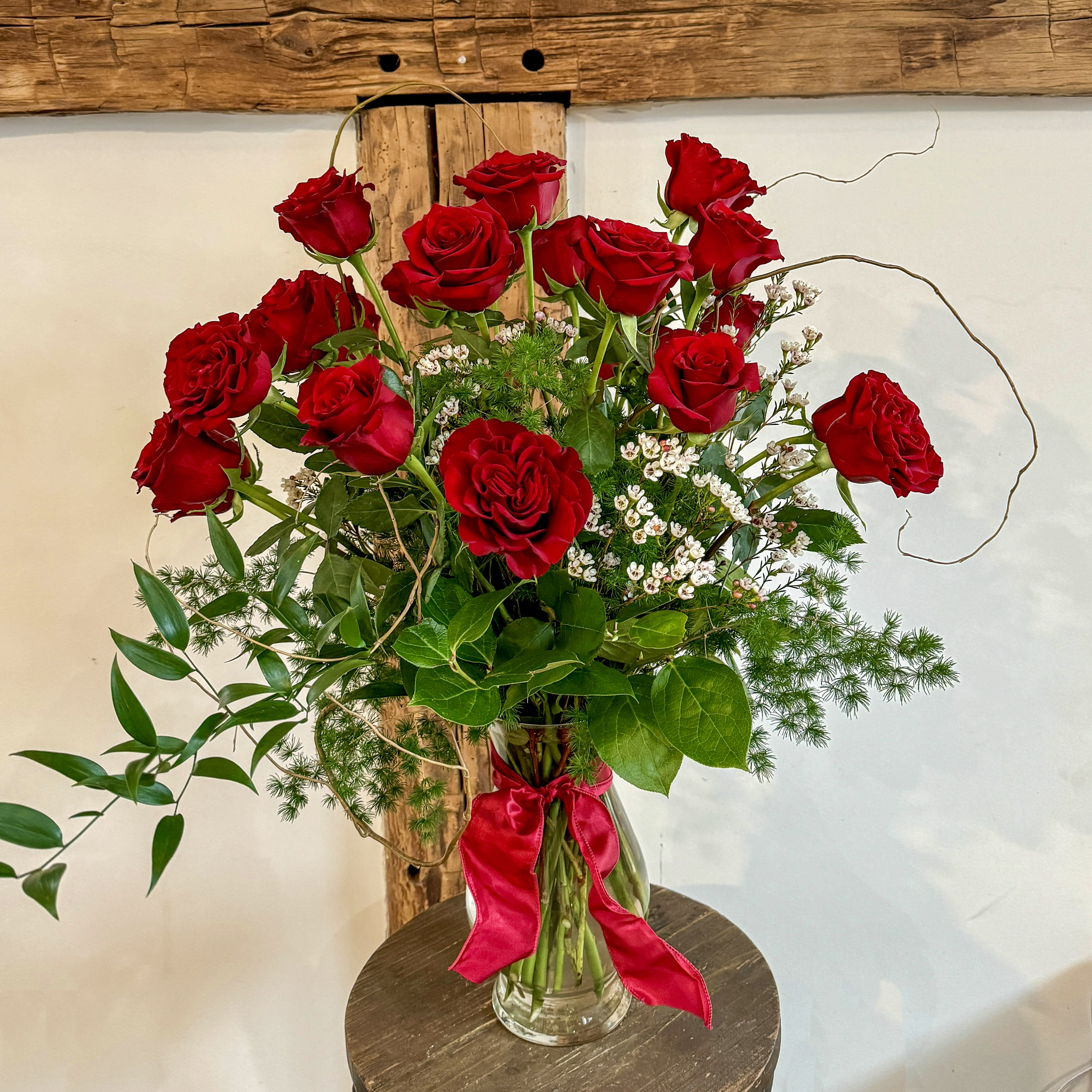 Classic Long-Stemmed Dozen Roses - Premium long stemmed roses in a tall and classic arrangement enhanced with a beautiful greens. Arrives with sculptural branch and waxflower accents. Upgrade to deluxe for 18 roses and premium for 24 roses.  Measures approximately 15&quot; x 28&quot;. 