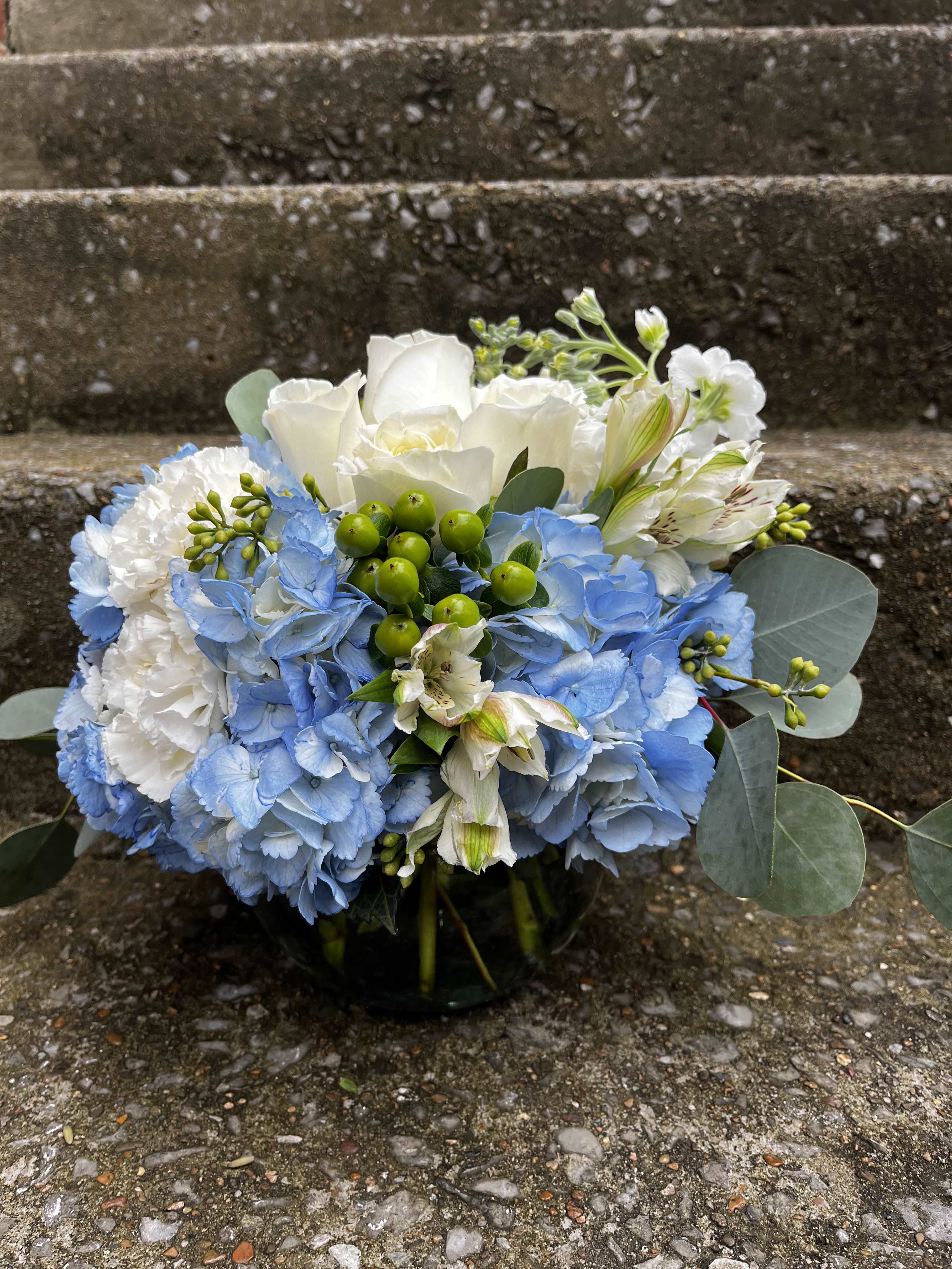 Pure Liberty - This arrangement has blue hydrangea, white carnations, white alstroemeria, green Hypericum, white roses, white stock and beautiful greenery.