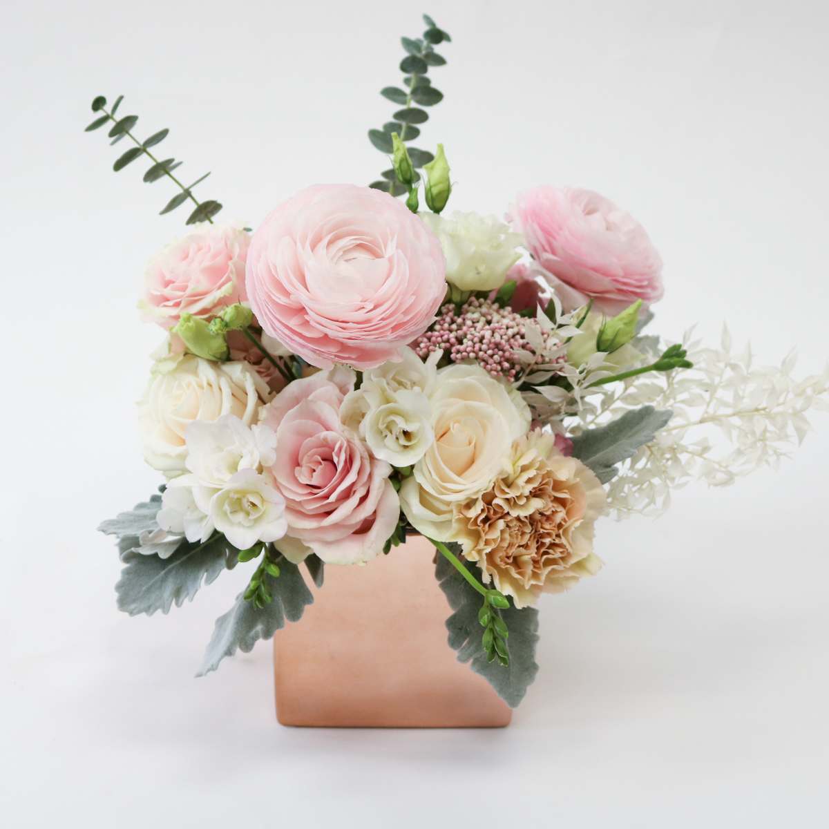 Pretty in Pink - Lovely ranunculus, delicate roses, and freesia, with a touch of dried Italian ruscus combine in this arrangement soft pink shades enough for your hearts content. Comes in a lovely square, rose gold vase.