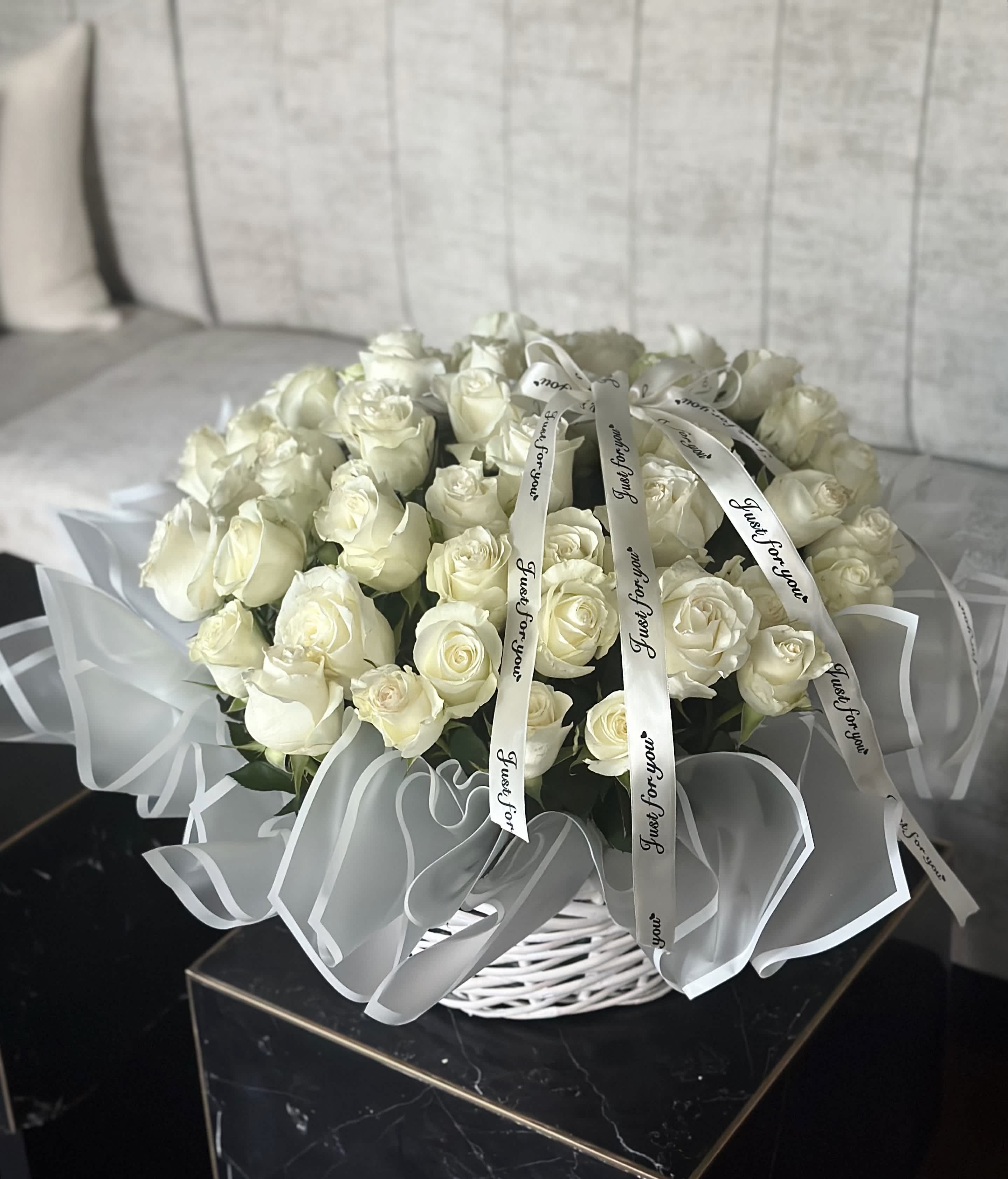 White Basket with White Roses - A white basket adorned with white roses and ribbons exudes timeless elegance and sophistication. The pristine white hue of the basket serves as a perfect canvas to highlight the pure beauty of the white roses. Delicate ribbons, gracefully woven around the basket, add a touch of whimsy and refinement to the arrangement. The combination of white roses and ribbons creates a classic and graceful aesthetic, making it an enchanting centerpiece for any occasion. Whether as a gift or as a decorative accent, this white basket with white roses and ribbons is sure to evoke feelings of purity and charm. 