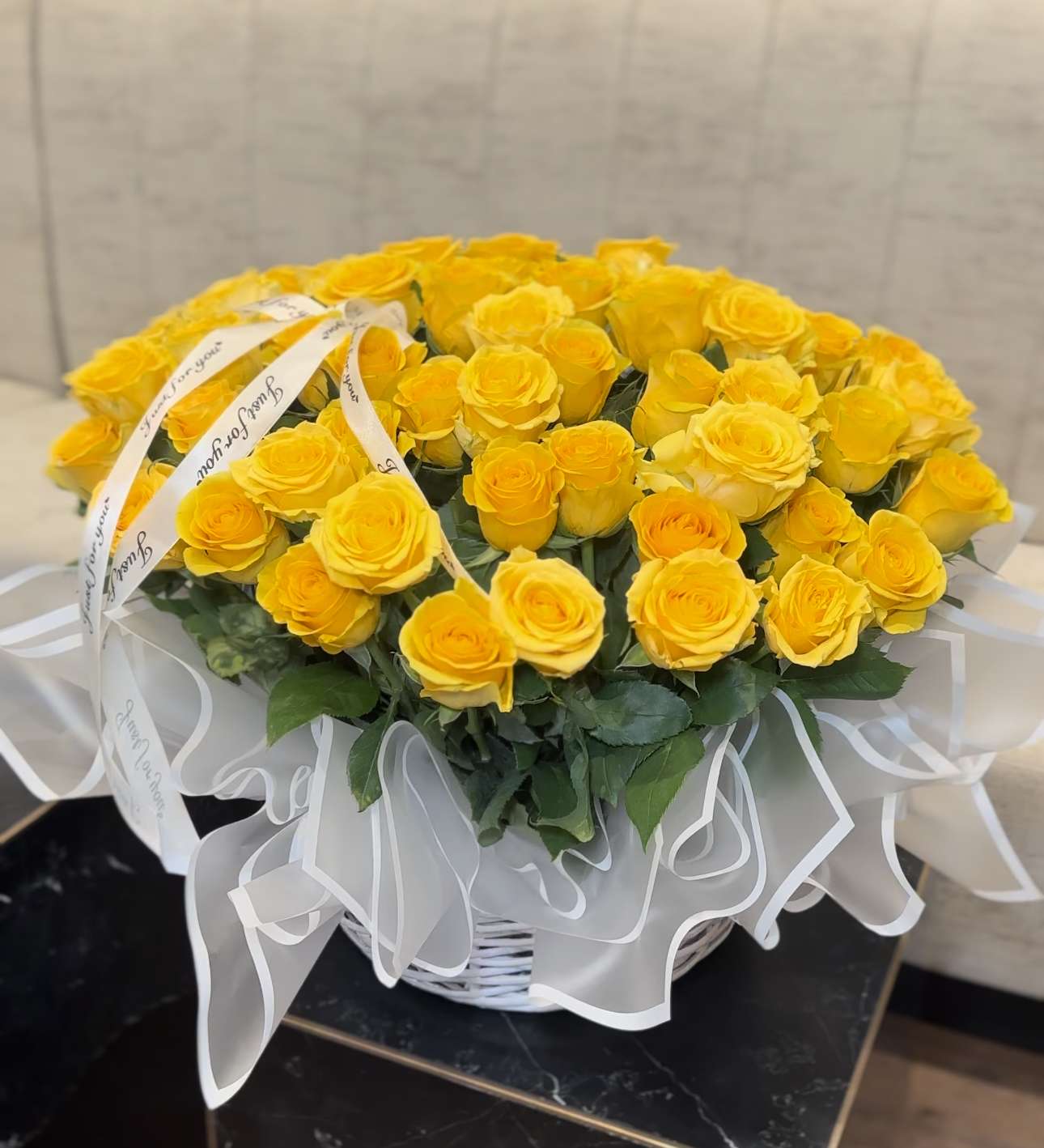 White Basket with Yellow Roses - A white basket, akin to a gown for the most delicate dreams, crowns the beauty of yellow roses, like drops of passion scattered across a snowy canvas. And the shimmering beads, like pearls of morning dew, lend an incomparable charm to the ensemble, magically framing this masterpiece of nature.