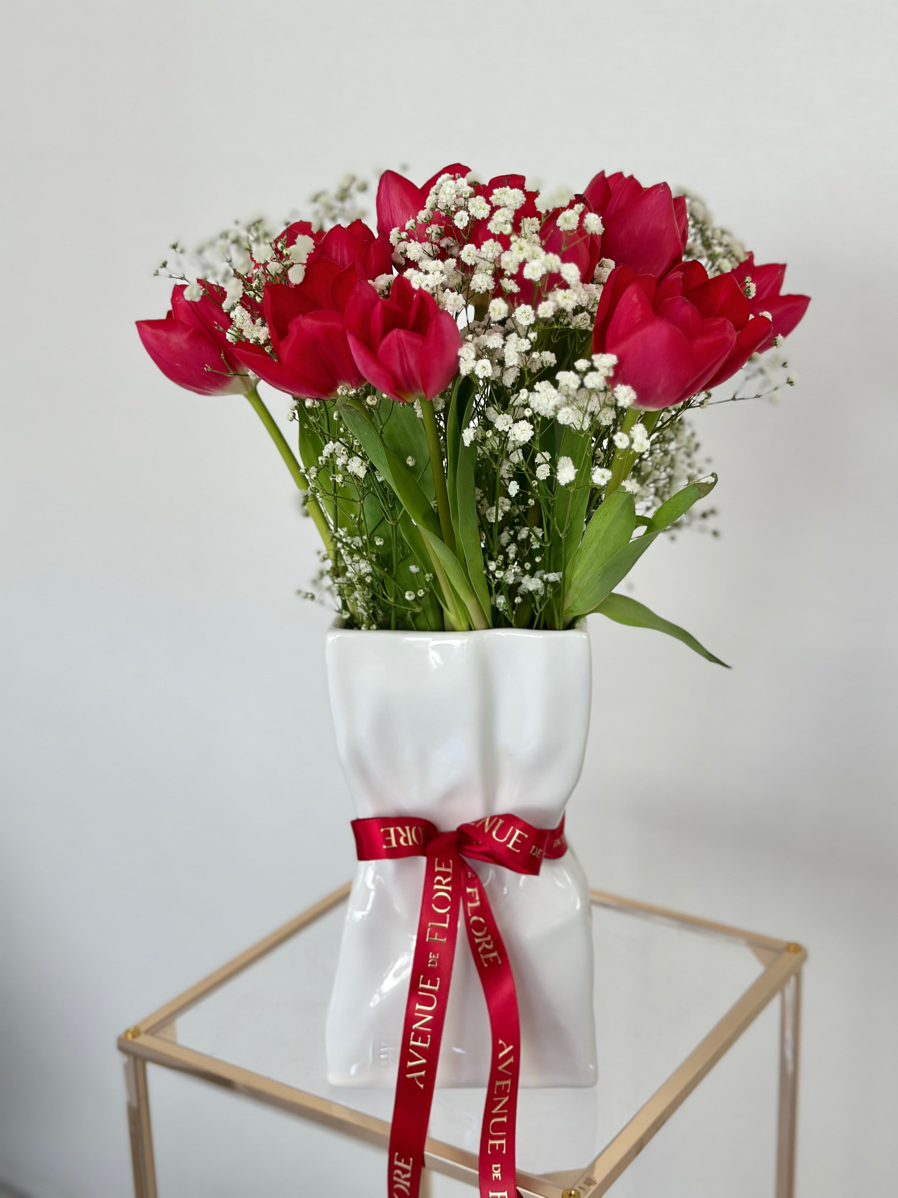 Tulip Glamour - Nestled within this sleek modern vase are vibrant red tulips, adding a pop of color and warmth to any space. This simple yet beautiful arrangement effortlessly brings a touch of nature's beauty into the home, infusing it with a sense of freshness and style. 