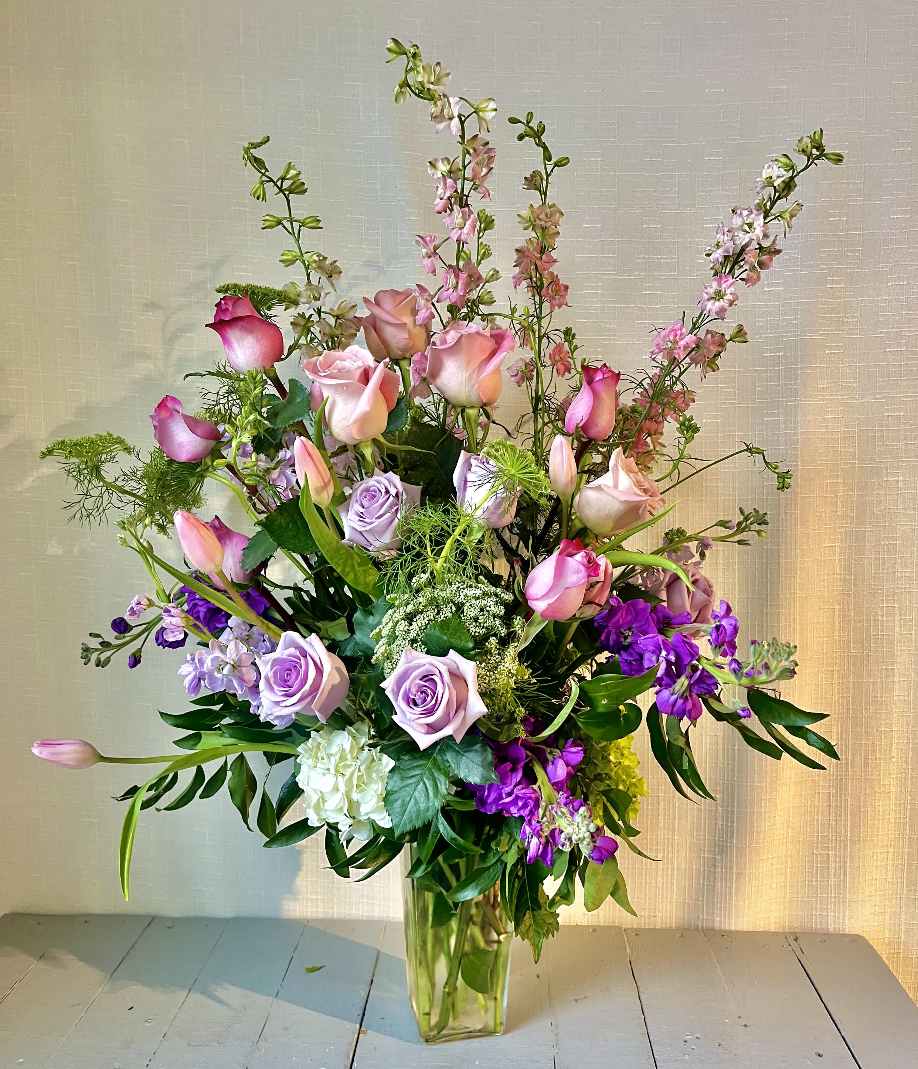 Purple Delight - &quot;Purple Delight&quot; is a lush collection of purple and white flowers with foliage designed in a clear vase.  For even more of an impact, allow us to upgrade your design to a Deluxe or Premium version, which will feature a larger quantity of stems and larger vase.  *Content may vary*