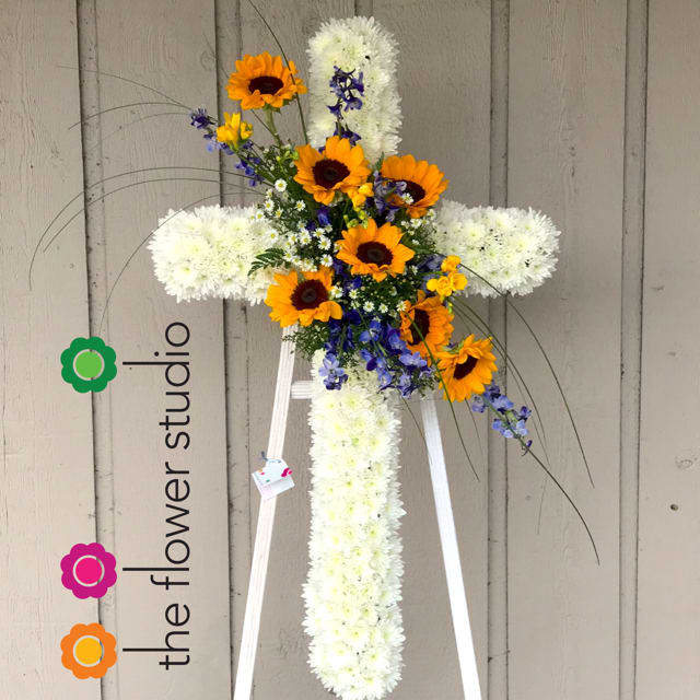 Divine Sunflower Tribute - A beautiful tribute -  devotion and hopes for eternal salvation are expressed with this gracefully elegant cross featuring a spray of sunflowers. Your faith and sincere condolences will comfort the family and friends attending the viewing / funeral. Flowers give people comfort and emotions. About 5 feet tall, including the standing easel. Colors may changed according with availability. 
