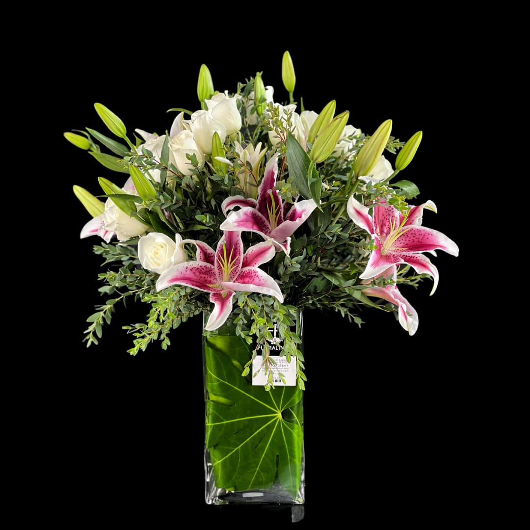 Dear Stargazer  - Modern yet classic presentation of White Roses &amp; Stargazer Oriental Lily flowers accompanied by Eucalyptus Parvifoila for sweet movement and texture. Soft colors and scents to bring subtle love notes.   Vase Dimensions:  16.00&quot; Height x 6.0&quot; Width x 6.00&quot; Depth (clear glass)
