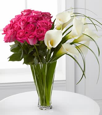 Irresistible Luxury Rose & Calla Lily Bouquet Irresistible Luxury Rose & Calla Lily Bouquet - Blooming with roses and open-cut calla lilies, this exquisite flower bouquet will bring wonder and elegant beauty into their every day. Brilliant fuchsia roses are arranged next to white open-cut calla lilies accented with lily grass glades for an impressive effect. Presented in a superior clear glass twist vase, this flower arrangement is a wonderful gift that will shower them with love and happiness. LX115