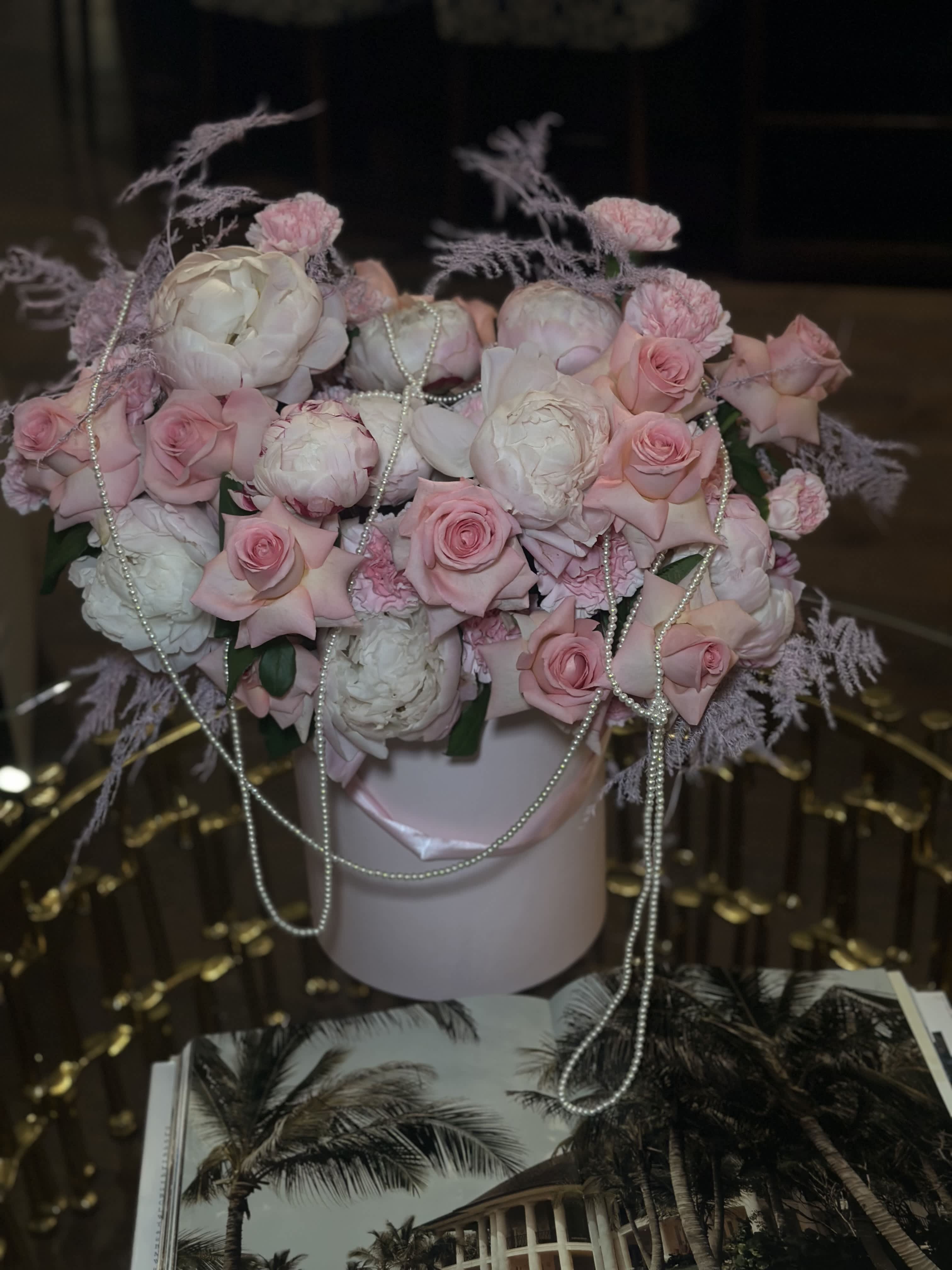 Peonies and pearl - Experience the epitome of elegance with our enchanting pink arrangement, showcasing the lush beauty of peonies, the timeless allure of roses, and the delicate sophistication of pearls. Each element is meticulously chosen and artfully arranged to create a masterpiece of floral design. The soft pink peonies and roses blend seamlessly, their petals forming a luxurious tapestry of color and texture. Interspersed with glistening pearls, this arrangement exudes a sense of opulence and grace, making it perfect for special occasions or as a breathtaking centerpiece. Let this exquisite composition convey your deepest sentiments and bring a touch of refined beauty to any setting.