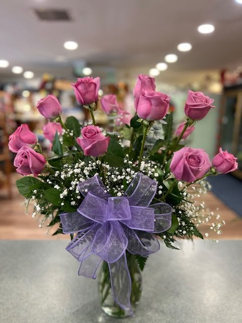 One Dozen Lavender Roses (R12L) - MAY REQUIRE 24hr Notice  One dozen long stem Lavender roses with assorted greens and accent flower finished with a coordinating bow.  