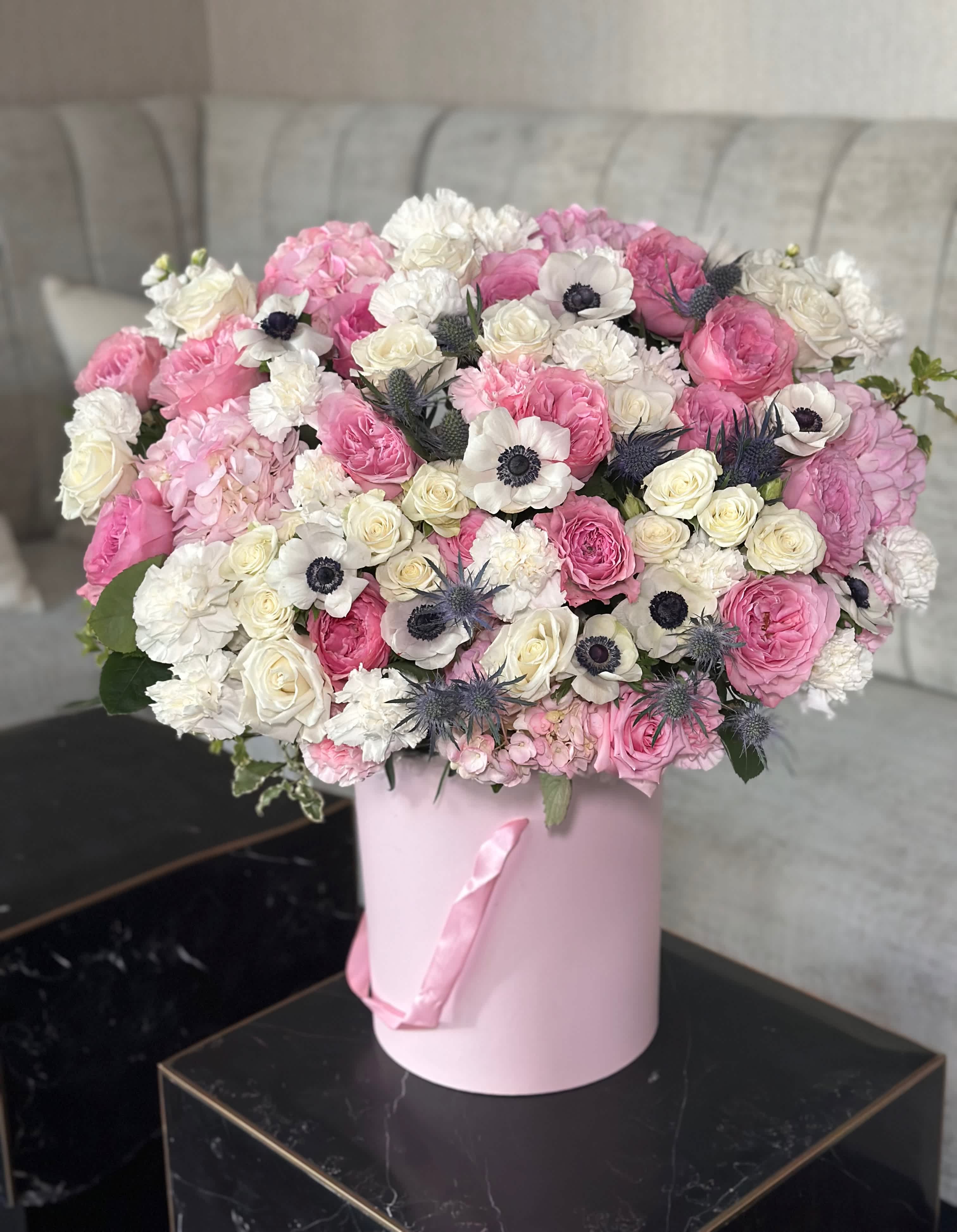 Fairy story Fairy story - In a charming pink box, a breathtaking arrangement awaits, exuding delicate beauty and elegance. Luxurious hydrangeas form a lush base, their soft petals creating a voluminous and romantic foundation. Nestled among them, roses bloom gracefully, their classic allure enhanced by the gentle blush of their hues. Dotted throughout, anemones add a touch of whimsical charm, their striking centers providing a captivating focal point. This pink box of blooms, brimming with hydrangeas, roses, and anemones, is a delightful symphony of floral splendor, perfect for any occasion.