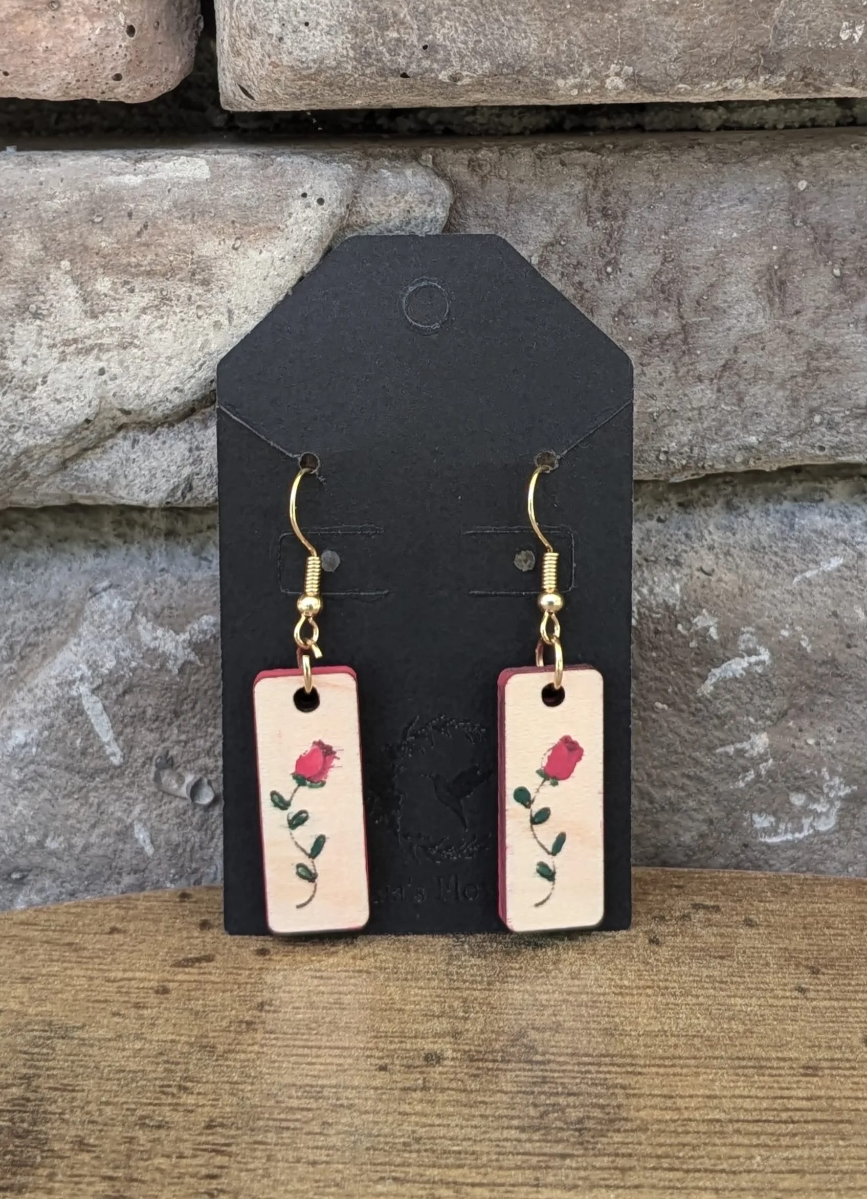 Roselight Earrings - Adorn your ears with the natural beauty of these unique earrings, meticulously handcrafted by Virginia artisans. Each pair features smooth maple wood discs, carefully laser-engraved with delicate rose designs that capture the essence of nature's elegance.  The engraved roses are then lovingly hand-painted in vibrant acrylics, showcasing the artistic skill and individual touch of the artisans. A protective layer of resin is applied to seal and enhance the colors, ensuring their lasting beauty.  No two pairs are exactly alike, making these earrings a truly special and personal accessory. Embrace the one-of-a-kind charm of these handcrafted treasures and let the vibrant colors and intricate details elevate your everyday style.  Features:  Materials: Maple wood, acrylic paint, resin Technique: Laser engraving, hand painting Origin: Handcrafted in Virginia, USA Style: Unique, nature-inspired
