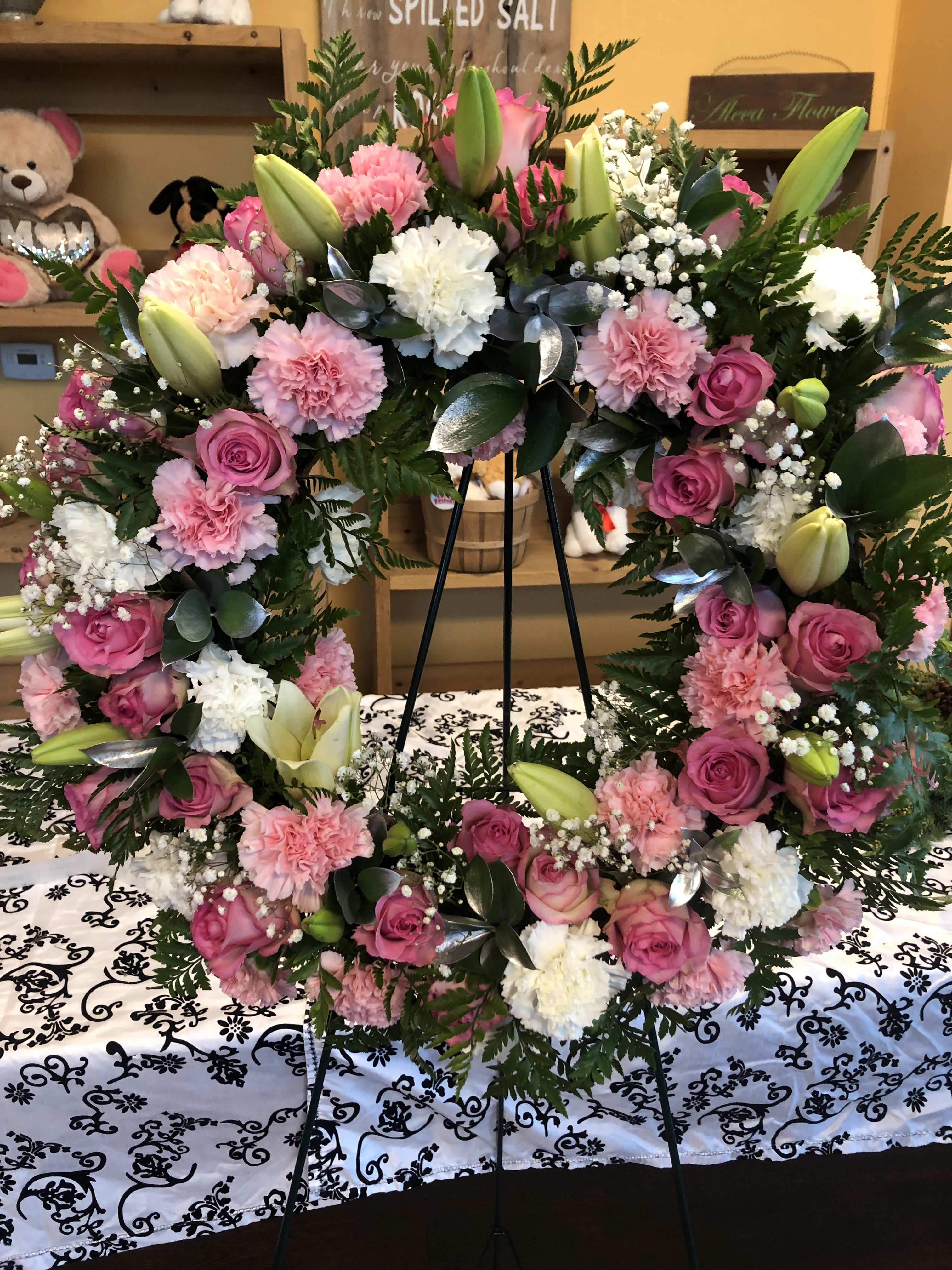 PINK AND WHITE (DESIGNER CHOICE WREATH) PINK AND WHITE (DESIGNER CHOICE WREATH) - MIXTURE OF PINK AND WHITE FLOWERS WITH SILVER RUSCUS LEAVES. FLOWERS TO INCLUDE ROSE, CARNATION AND LILIES, BABY BREATH AND SILVER RUSCUS. STANDARD PRICE IS AN 18 INCH WREATH TO INCLUDE 25 ROSE DELUXE IS AN 22 INCH WREATH TO INCLUDE 36 ROSES PREMIUM IS A 24INCH WREATH TO INCLUDE 42 ROSES