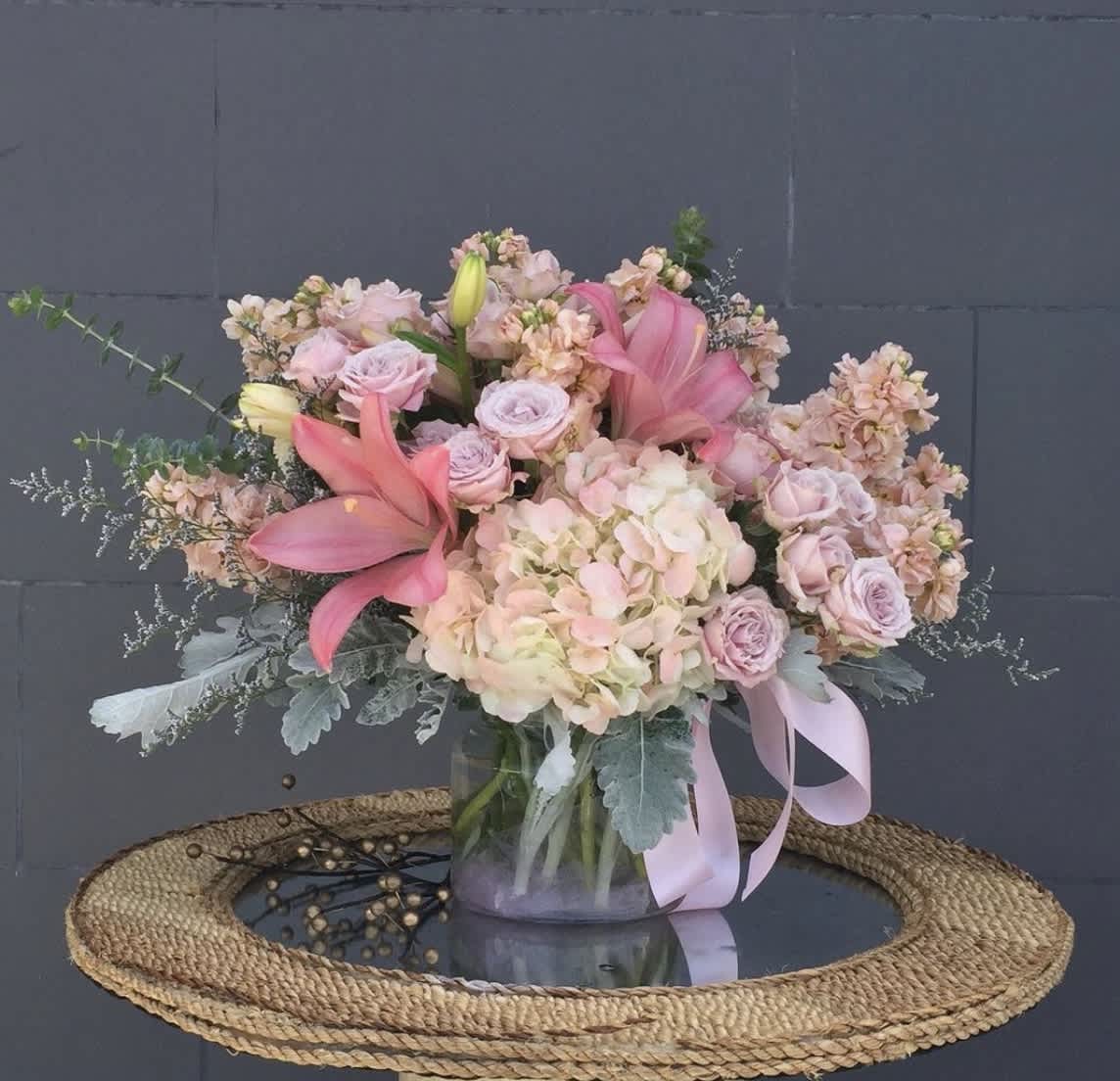 Sweetest Scent - Beautiful pink and lilac vase arrangement featuring lilies, hydrangeas, roses, stock, and green accents. 
