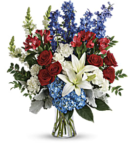 Patriotic Tribute Patriotic Tribute - A glass vase filled with patriotic colors of Blue Hydrangea, Blue Delphiniums, White lily, White Snapdragons, Red Roses, White Carnations, Dusty Miller and Salal.