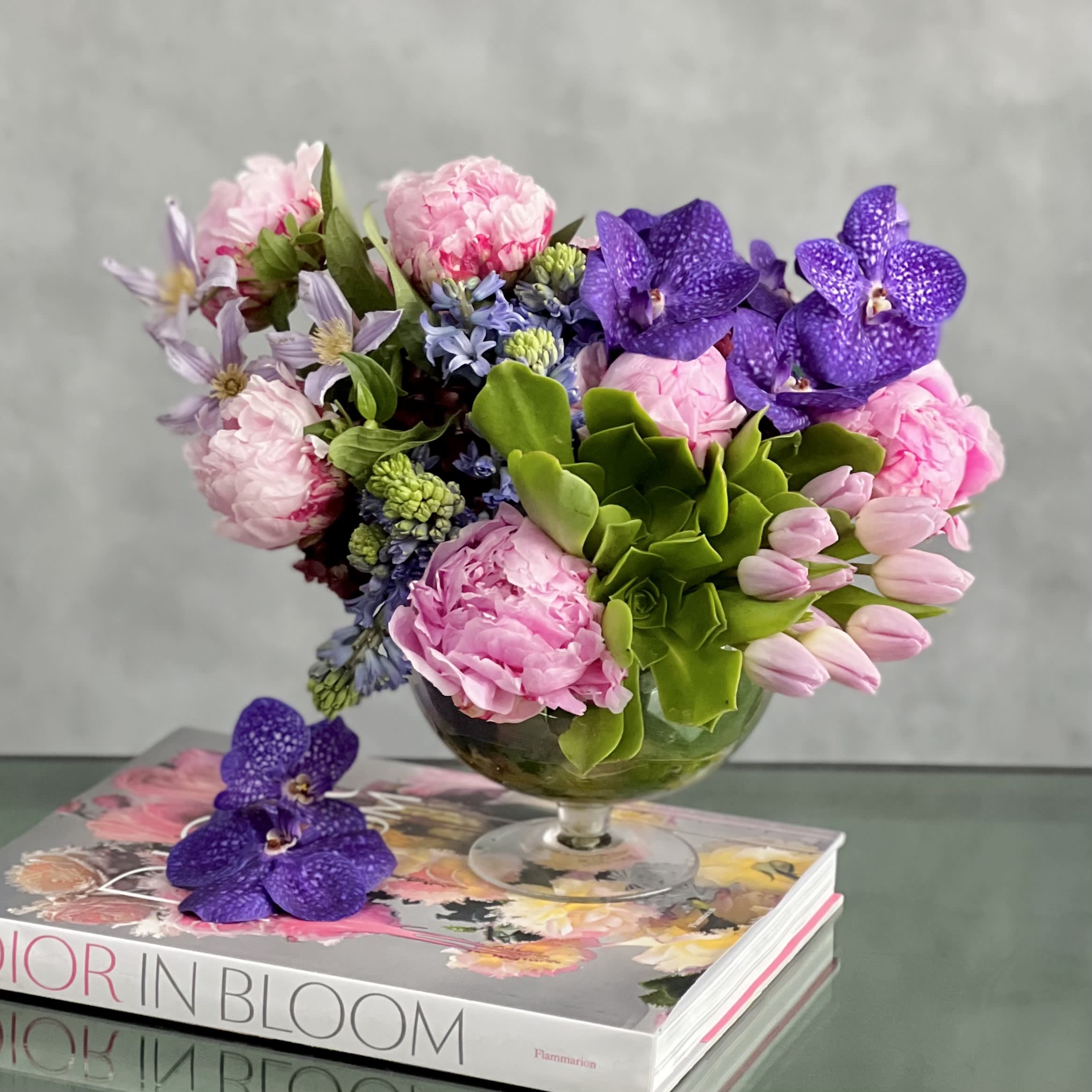 Peonies and Vanda Bowl - Experience a touch of luxury with our exclusive floral arrangement crafted by our top-tier florists, available for same-day delivery. This exquisite creation features a stunning mix of Vanda orchids and lush peonies elegantly showcased in a sleek modern glass vase. The perfect fusion of sophistication and natural beauty, this arrangement is a reflection of refined taste and artistic craftsmanship.  Measuring at 11&quot; tall and 13&quot; wide, with the vase dimensions of 7x7, this arrangement embodies elegance and style. With fresh products and daily deliveries, our luxury florist ensures that each creation is a masterpiece tailored to elevate your space and uplift spirits with its beauty. Vase: 7x7