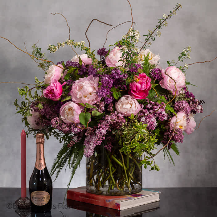 Grandeur in Bloom - Step into a realm of enchantment with our spectacular floral masterpiece, the Enchanted Lilac &amp; Peony Extravaganza. This grand display features a lavish abundance of lilacs and peonies, expertly arranged in a 30-inch-tall and 30-inch-wide 10x10 cylinder glass vase.   Transporting you to a world of pure elegance and beauty, this arrangement serves as the perfect grand entrance piece, commanding attention with its opulent blooms and luxurious design. Delight in the harmonious blend of lilacs and peonies, radiating a captivating fragrance and a visual feast of colors. Transform any space into a majestic setting with this stunning arrangement that exudes grace and grandeur.