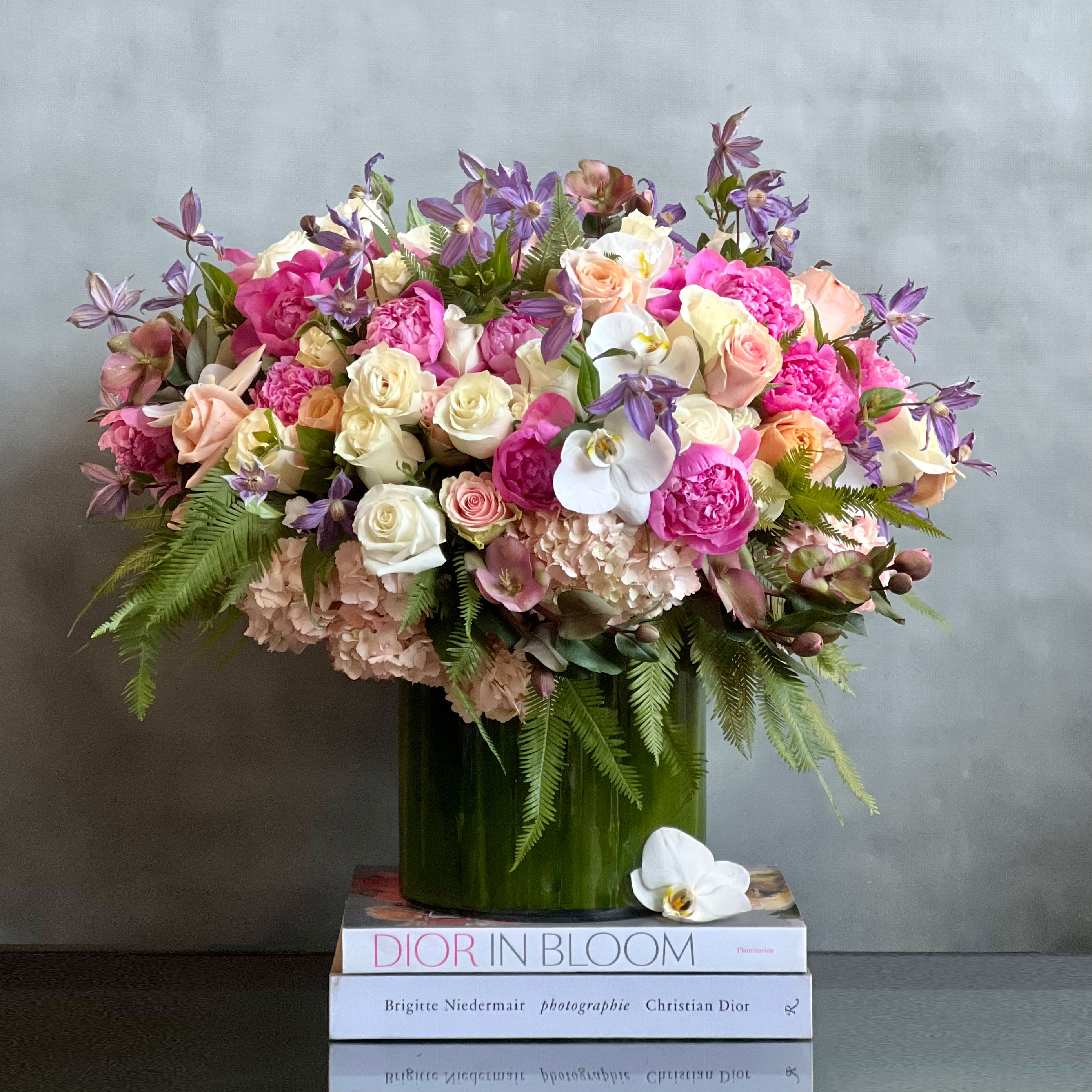 Blooming  - A large array of various blooms that add a subtle touch of color. A chic piece that includes, Peonies, Roses, seasonal greens, Orchids and Hydrangeas. A beautiful thought for that special someone in your life. 
