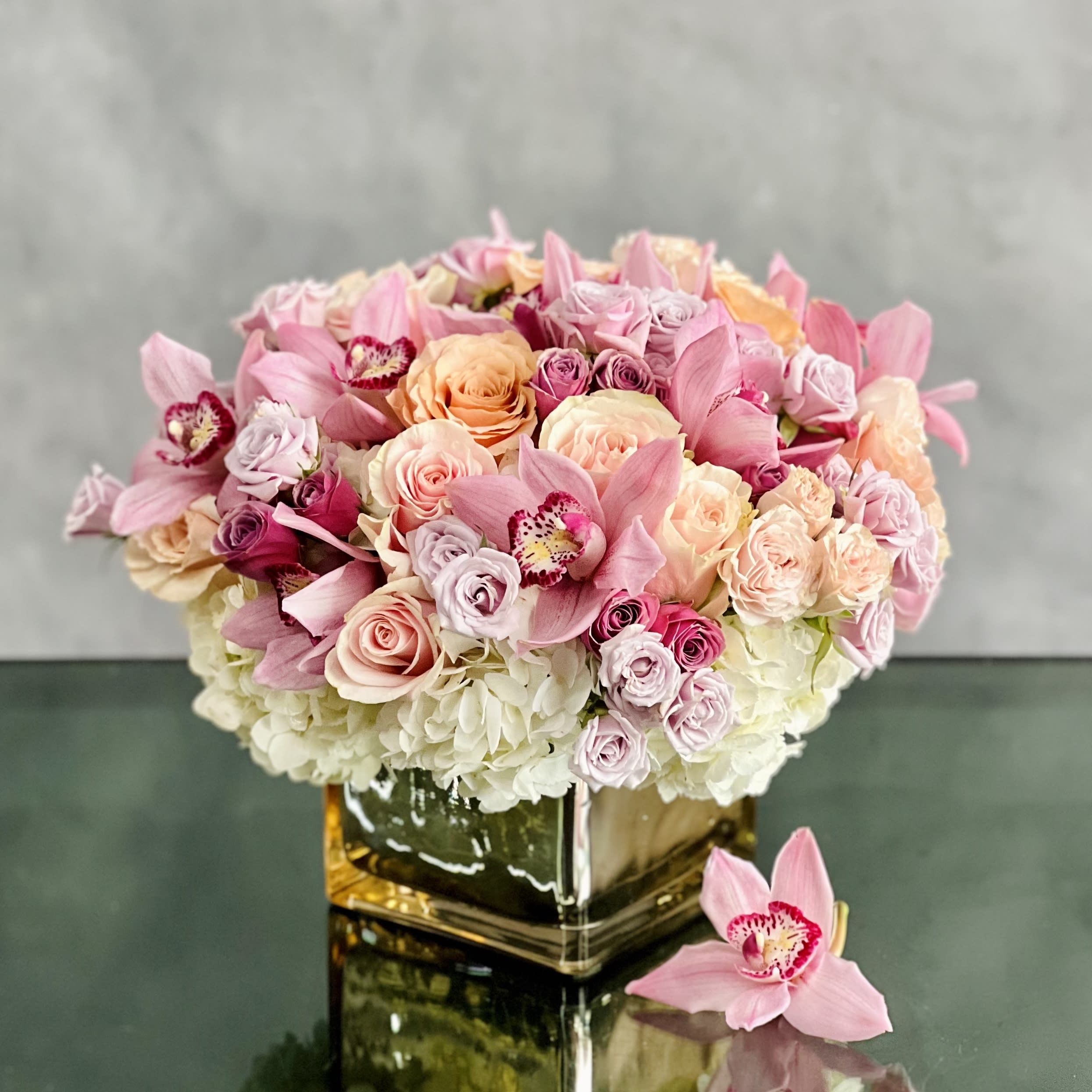 Gold Finger - A beautiful array mixed flowers that include Roses, Orchids and Hydrangeas in a Mirrored Gold Vase. A soft and romantic touch and a beautiful sentiment made to be the perfect gift or touch of happiness.  Approx. 17&quot; round