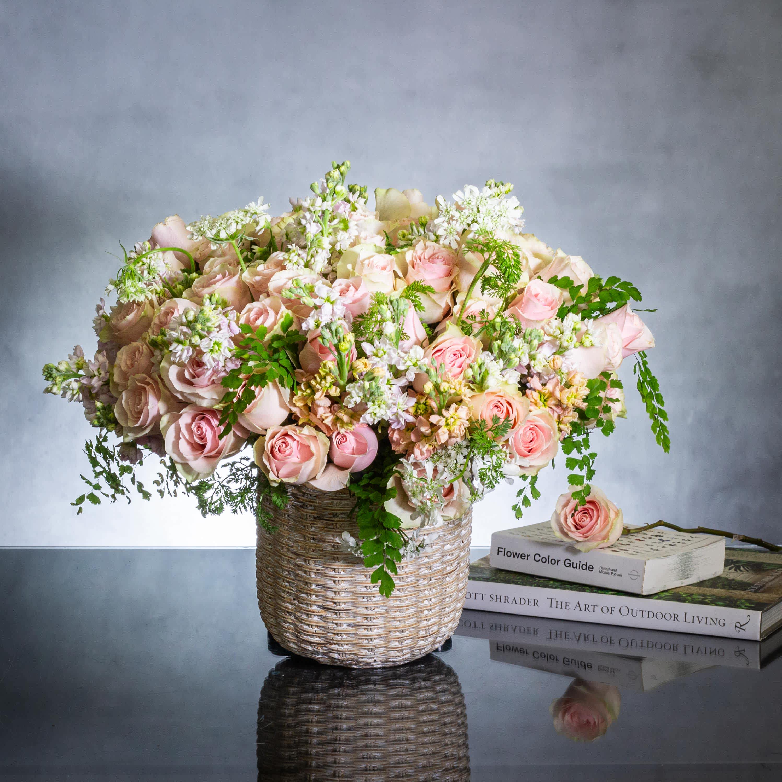 French Country Chic - Embrace the charming essence of a French country home with this exquisite floral arrangement nestled in a woman basket ceramic container. Overflowing with over 80 delicate pink roses, accompanied by fragrant local flowers and adorned with maiden's hair fern, this arrangement exudes elegance and grace in every petal.  An ideal choice for Mother's Day, this floral ensemble captures the beauty and simplicity of a French countryside garden. With same-day delivery available in Beverly Hills, surprise and delight your mother with a gift that epitomizes love, beauty, and the essence of a blooming spring garden.