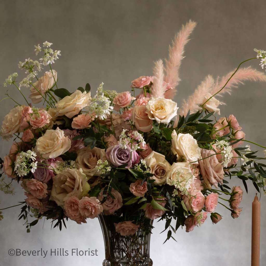 Come Fly with me - This stunning arrangement boasts over 100 blooms of gorgeous delicate florals, including 50 luxurious roses. Presented in a sophisticated glass pedestal vase, this statement piece exudes romance with its dreamy pastel colors. Perfect for Valentine's Day, this is truly a soft and elegant choice to express your love.
