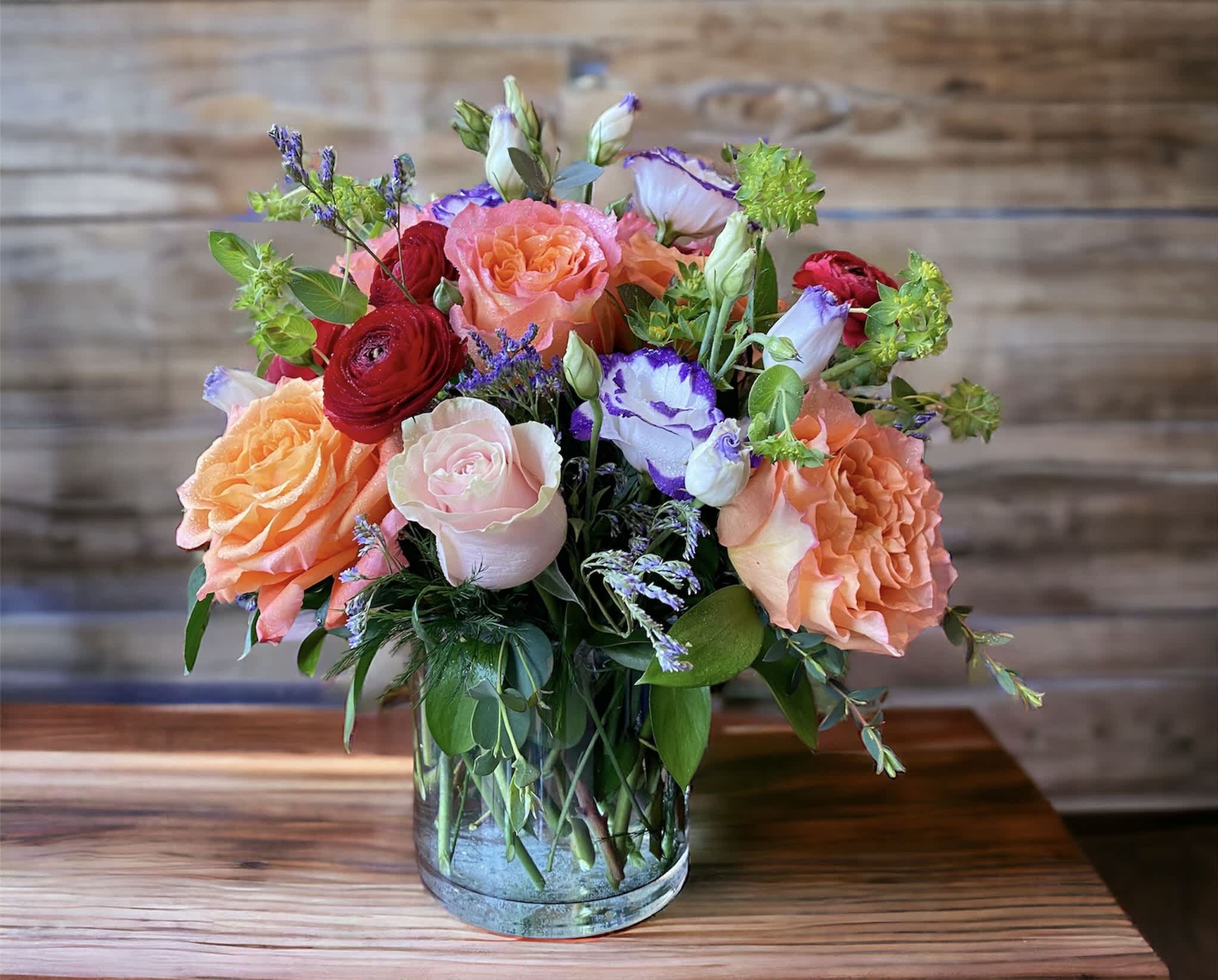 Uniquely Chic - Tres chic! Send that special someone a stylish sentiment with the bright colors of this modern arrangement. Summery pink, red, white and orange are contrasted by the cool clarity of a simple  vase. An eye-catching everyday choice! Orange, pink roses,  red ranunculus, white lisianthus  and a bit of understated greenery. Delivered in a clear glass vase.