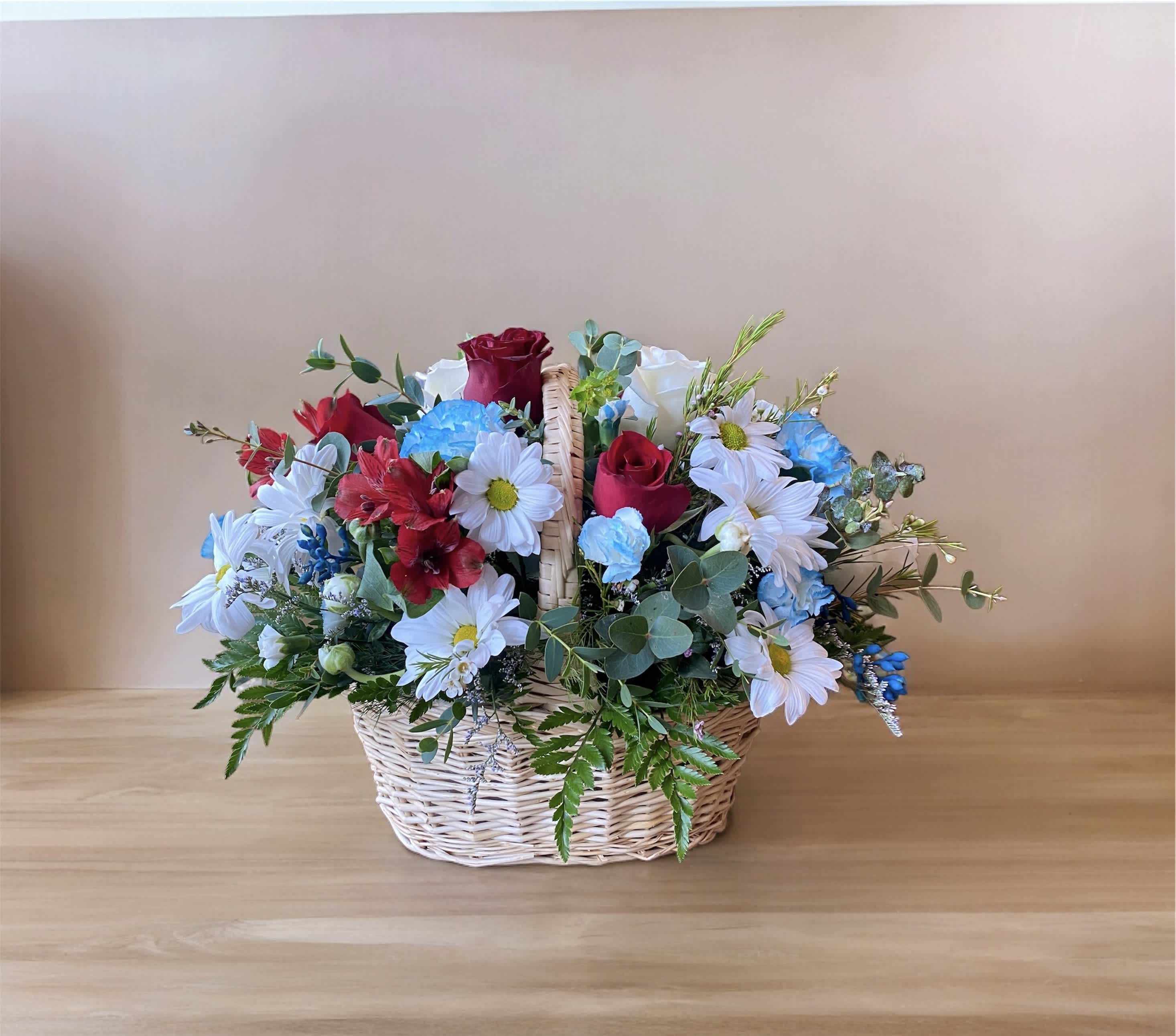 Greater Glory Basket - This arrangement features a patriotic display of blue, red and white florals. Whether it's to honor the life of someone who served our country or comfort a family member, this arrangement makes a fitting gift for a tabletop display at the service or delivered to a loved one's home. Please Note: The bouquet pictured reflects our original design for this product. While we always try to follow the color palette, we may replace stems to deliver the freshest bouquet possible, and we may sometimes need to use a different basket.
