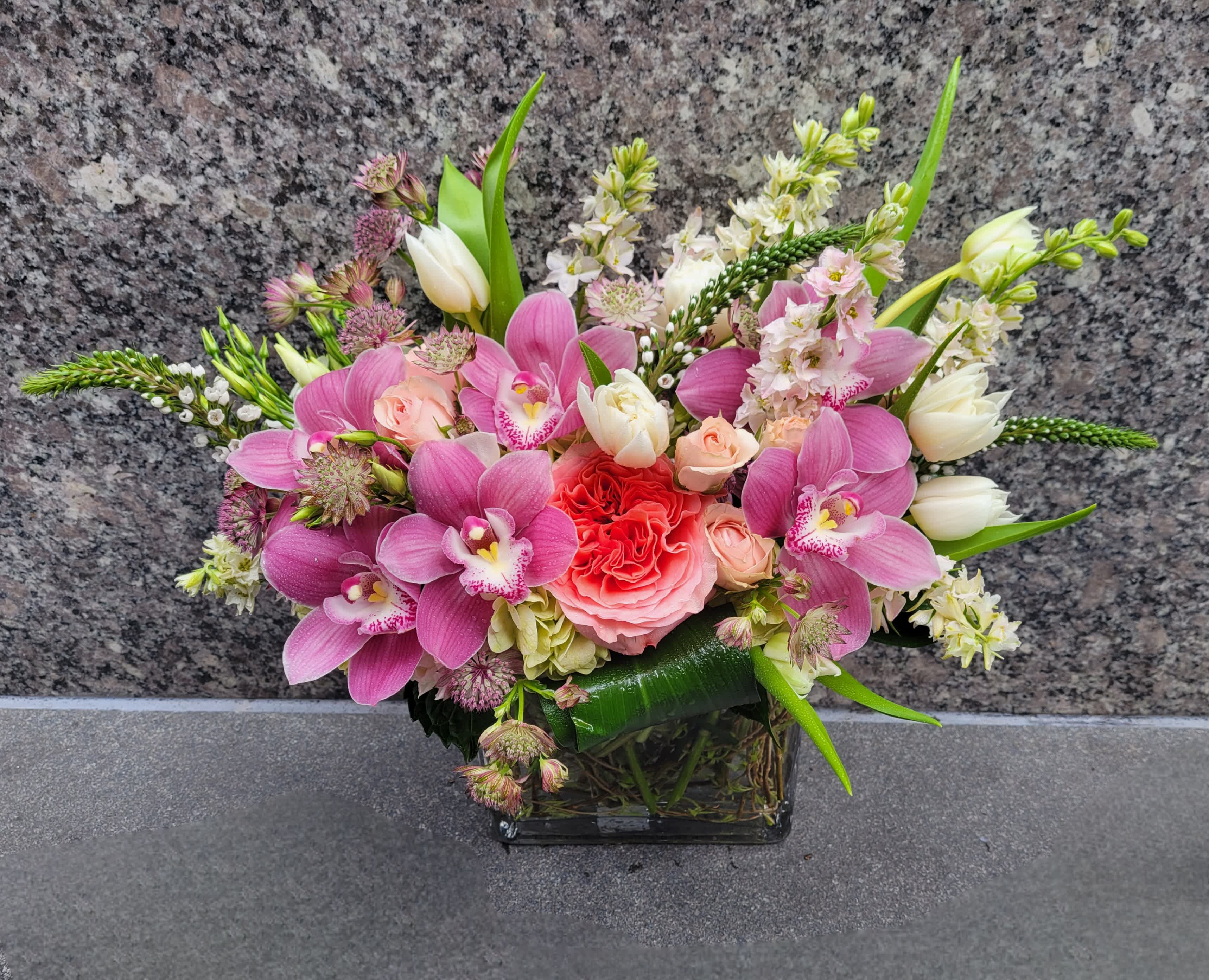 Monte Cristi - Radiant pink cymbidium orchids, soft garden roses, and pristine white tulips dance amidst a backdrop of vibrant spring flowers, creating a symphony of color and fragrance that captures the essence of the season's beauty