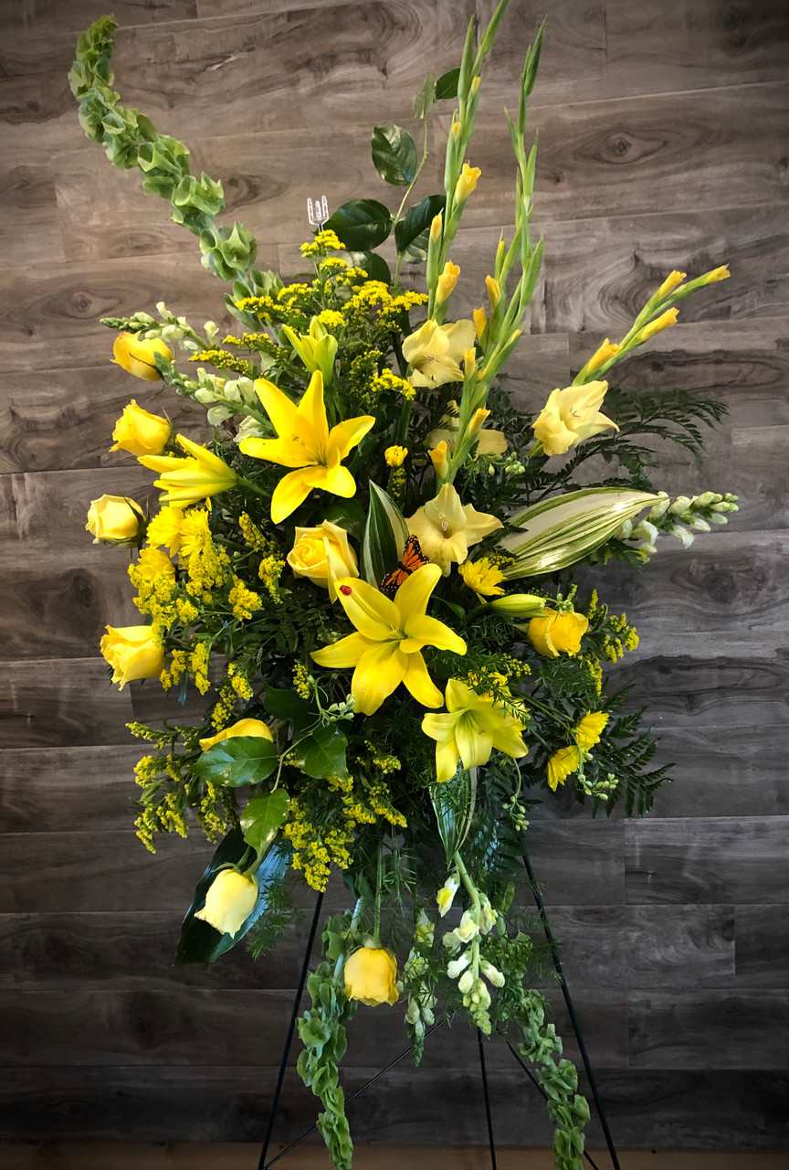 Rays of Sunshine - Nothing shows your sentiments of friendship better than this glowing display of yellows. Lilies, roses, glads, and solidago are stars shining amid classic greens and belles of Ireland - all regally displayed on a standing easel.  This arrangement can be done in other color schemes as well.