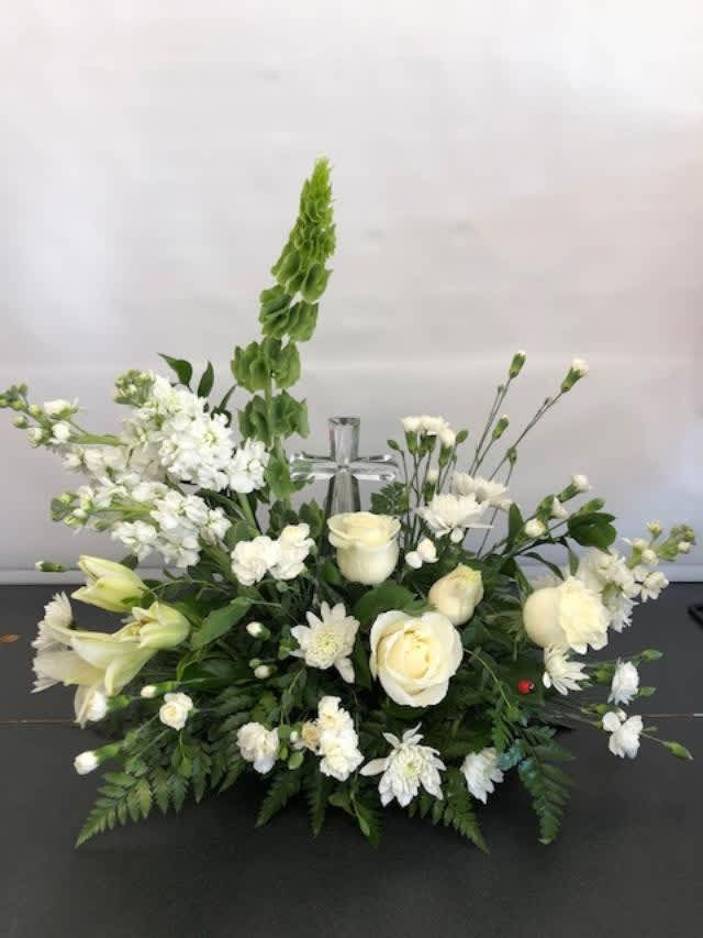 Crystal Cross - Pure white blooms including roses, carnations and mums, surrounding a clear crystal cross keepsake amid a sea of greens.