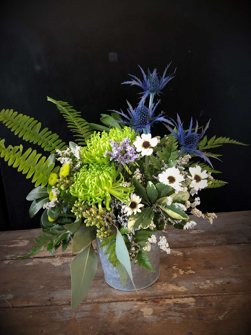 Serenity Serenity - The spirit of calm, clean air and peace abound in this peaceful modern arrangement of green spiders, blue thistle and ying yang daisies, a unique and modern arrangement that will work for nearly any occasion.
