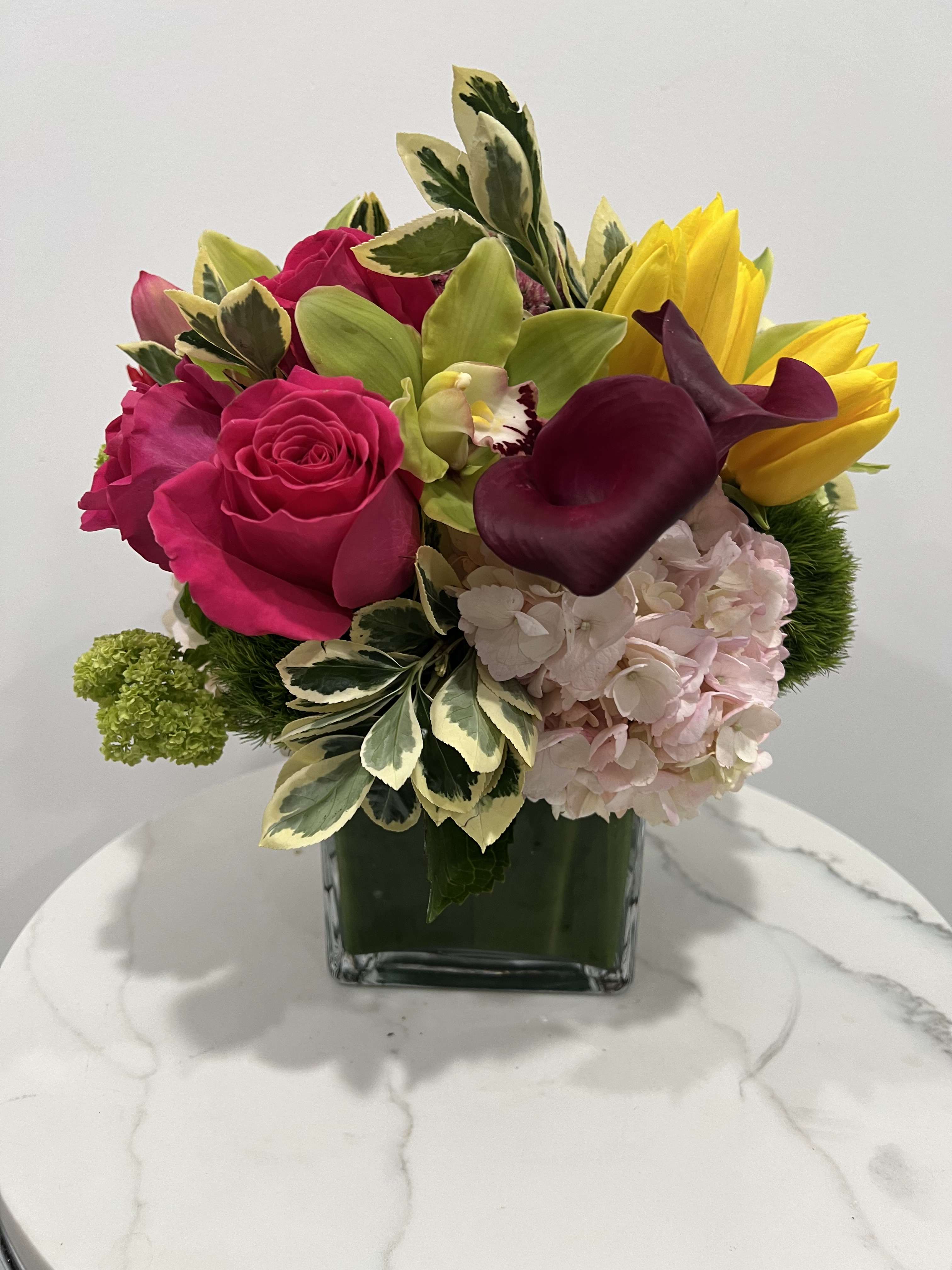 Vibrant Harmony Ensemble - Indulge in the vivid beauty of our Vibrant Harmony Ensemble. This striking arrangement showcases a captivating mix of colors, including vibrant pink roses, bold purple calla lilies, vivid pink hydrangeas, and sunny yellow tulips. Each bloom exudes its own radiant energy, coming together in perfect harmony to create a visually stunning display. Whether as a centerpiece for a special occasion or a thoughtful gift to brighten someone's day, this ensemble is sure to leave a lasting impression with its vibrant hues and elegant charm.