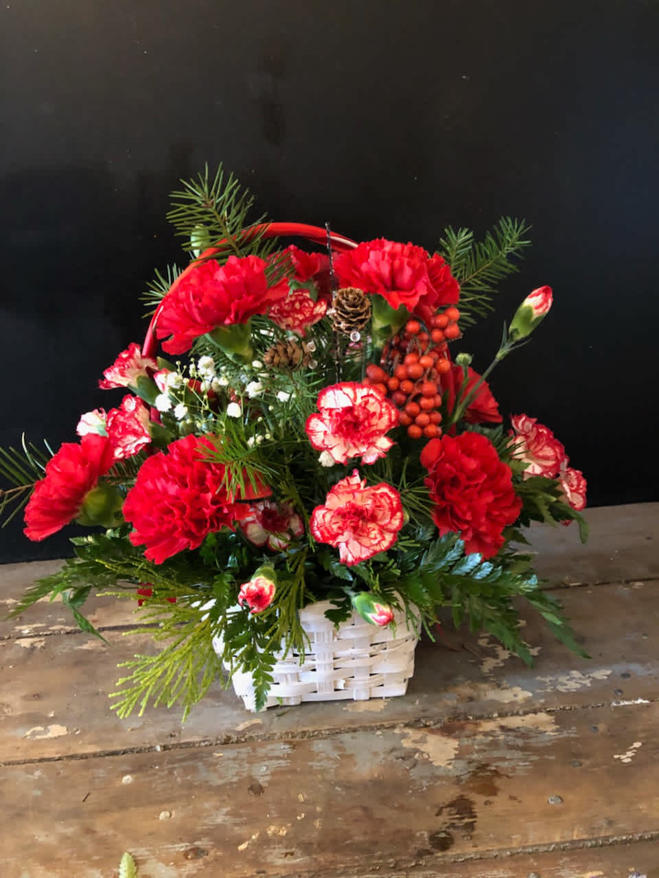 Christmas Basket Christmas Basket - A basket filled full of red and white carnations with winter greens will put all who see it in the Christmas spirit.