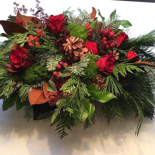 Holiday Table Centerpiece - A low foam tray filled with cascading seasonal Holiday greens and flowers.  Imagine the scent of cedars, spruce, pine and eucalytus in a bowl and this is what you'll enjoy for at least two weeks during the holiday season.    The Large and X-Large sizes feature a low wide ceramic vase bursting with fragrant holiday greens, magnolia and berries, topped with fresh roses and seasonal flowers.     Small 18&quot;  $75  Medium 24&quot; $120  Large 30&quot; in ceramic tray $170     Don't forget to consider one of our Artisan cards to add to your order.  Each card is designed by a local artist and is available in four different varieties. Store cards are also available.  x-Large 36&quot; in ceramic vase $230