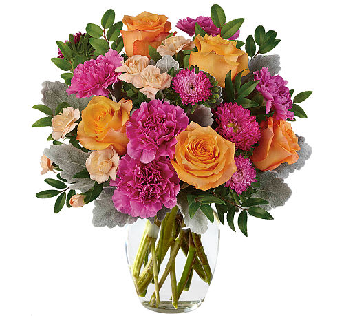 Island Escape  bouquet - Transport yourself to a tropical paradise with our Island Escape floral arrangement. Housed in an elegant glass vase, this vibrant bouquet features a stunning mix of lush orange roses, bold hot pink carnations, delicate peach mini carnations, and striking hot pink asters, all accented by fresh greenery.