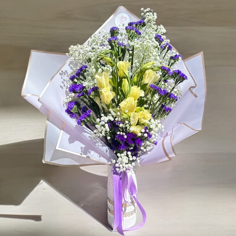 Selene's Lunar Harmony #10 - Capturing the essence of harmony, “Selene’s Lunar Harmony” draws inspiration from Selene, the Greek goddess of the moon. This arrangement showcases the tranquil beauty of lisianthus, woven with mystical shades of purple limonium and the delicate allure of gypsophila. Purple wrap mirrors the moonlit sky. Let this bouquet infuse your life with lunar serenity and celestial magic.