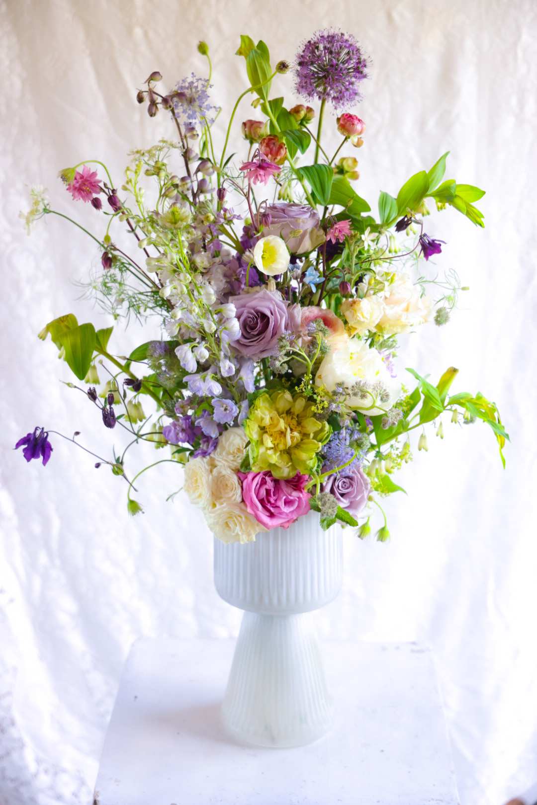 Garden of Curiosities Arrangement - Let Stacy take you on a summer garden walk. Where each unfurling blossom is unique. Heady fragrances linger, and beyond each leaf, a new bloom appears. An arrangement to fascinate and adore.    One of a kind by floral designer Stacy Leafsong Arrangements will be delivered by 7pm, for a specific delivery time please include in special instructions. On holidays, our busiest times, deliveries will be made by 7:30pm.