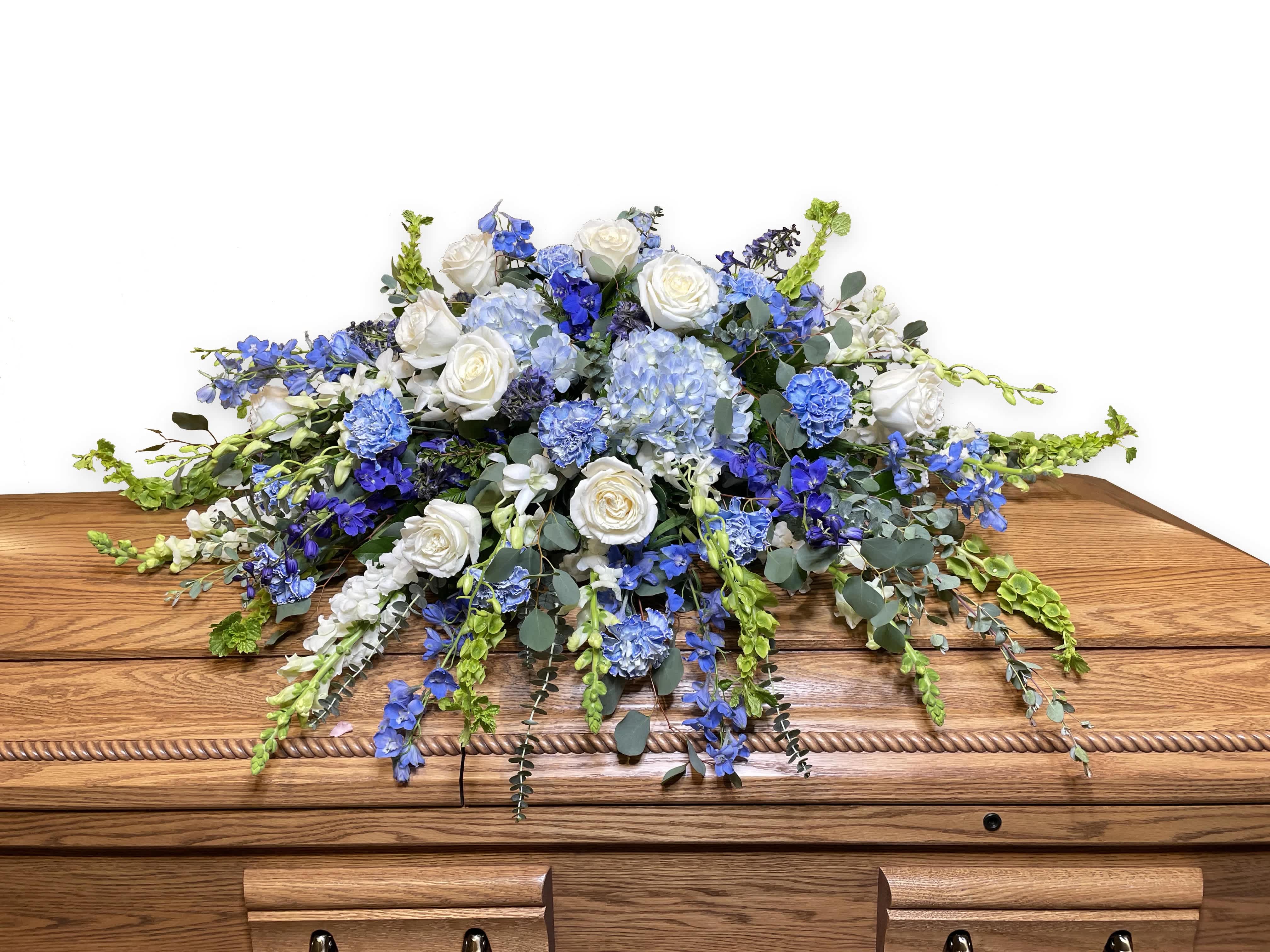 Peaceful Half Casket Cover - Honor a life so beautifully lived with a proud display of blue and white blooms. Our half casket cover, crafted with care and artistry by our expert florists with blue delphinium, white roses, and accented with blue hydrangeas , is an unforgettable way to commemorate a lifetime of loving devotion.