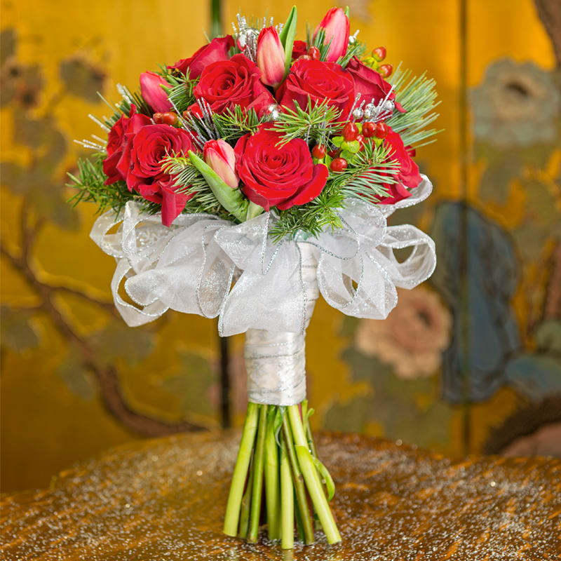 WINTER ROSE BOUQUET WINTER ROSE BOUQUET - A MIX OF RED ROSES, RED TULIPS, RED BERRIES, ALL GATHERED WITH A STUNNING GLITTERY BOW AND SILVER BLING THROUGHOUT.