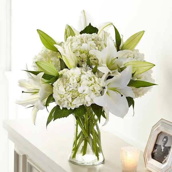 Compassionate Lily Bouquet - Classic lily and hydrangea blooms are arranged by our talented designers to create our Compassionate Lily Bouquet. Each white bloom elegantly brings solace and comfort to those experiencing a loss.