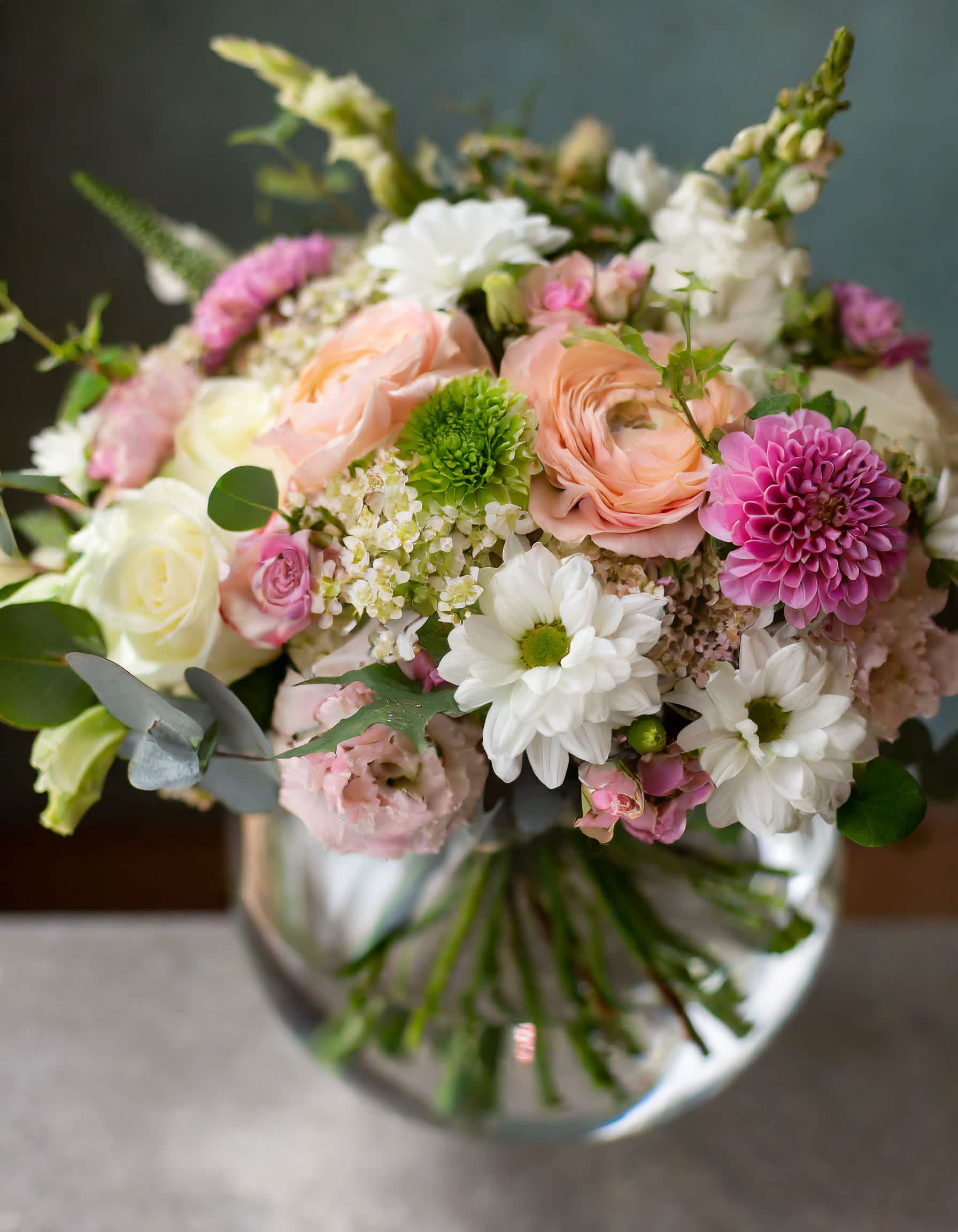 Mixed bouquet of pink, white, and peach flowers in a glass vase