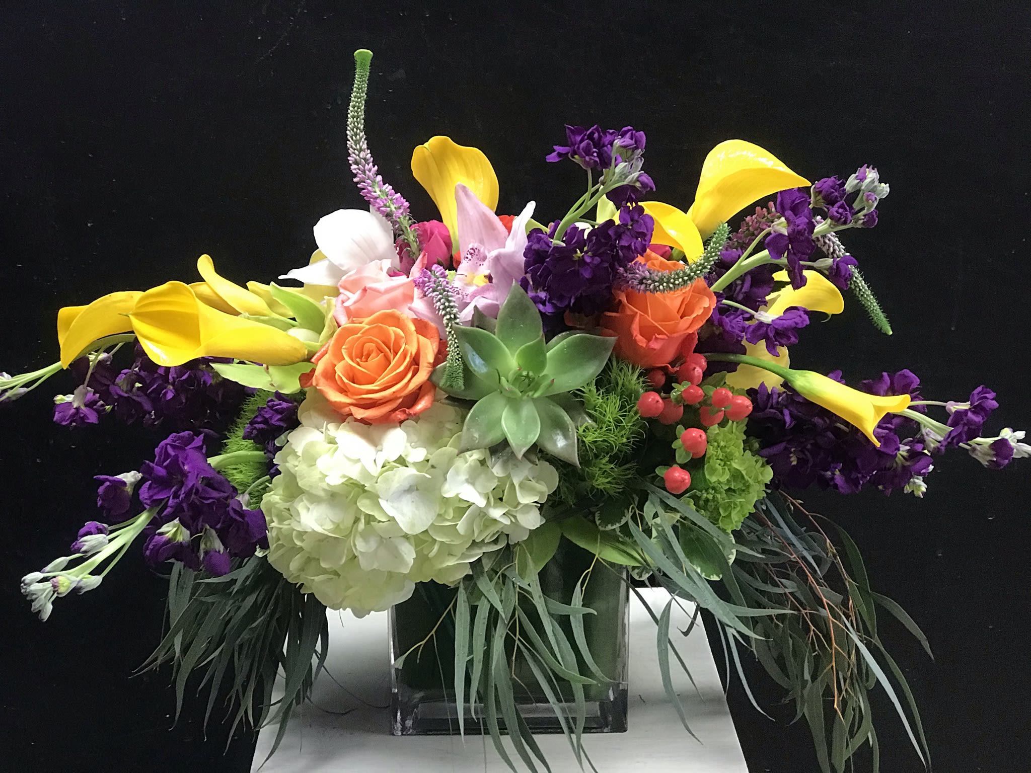 Overflower - A verdant spilling-all-over table piece featuring callas, textured greenery, succulents, and orchids. 