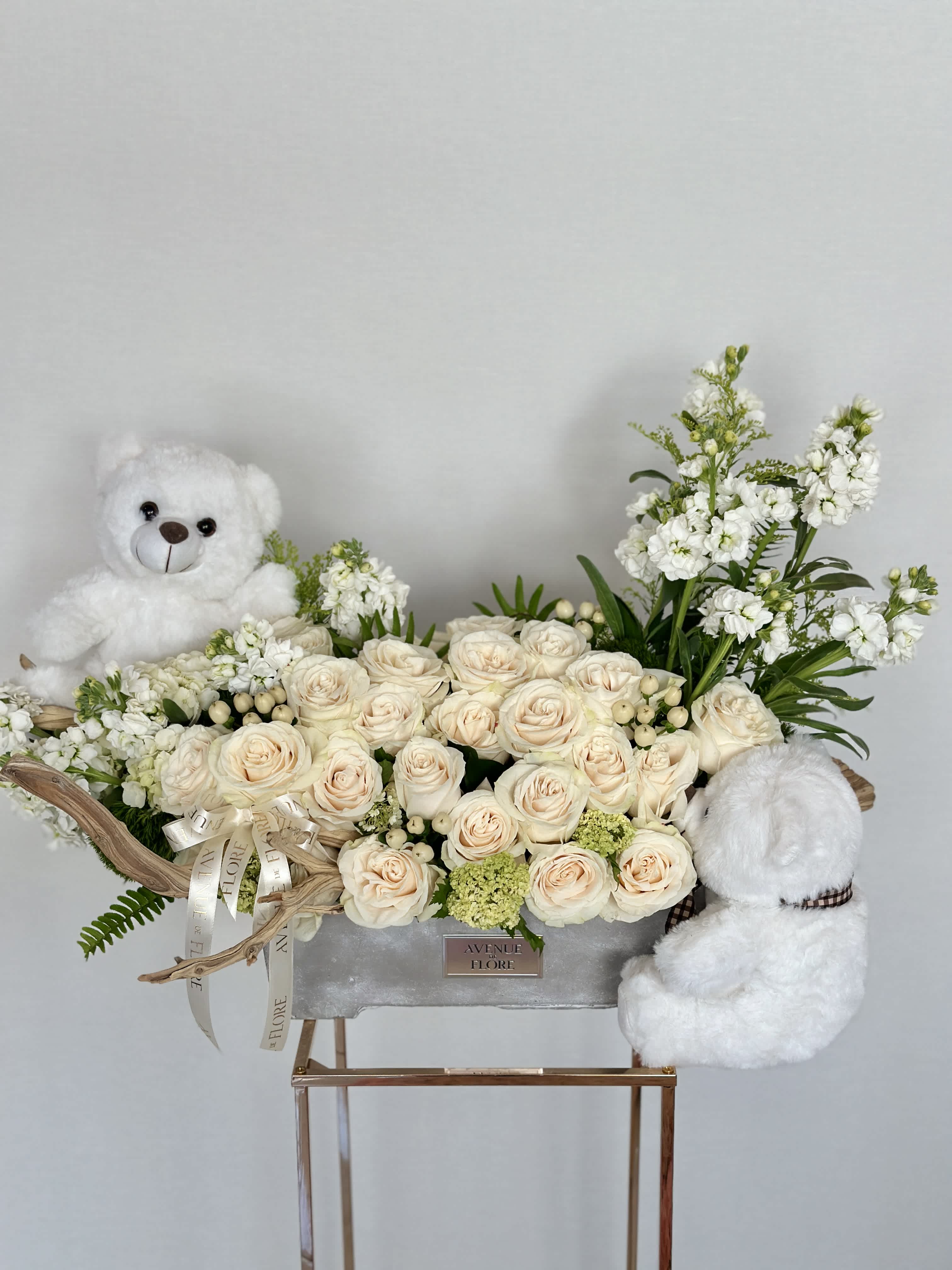Teddy Bear's Garden - A breathtaking floral arrangement, crafted to welcome a precious newborn into the world. The focal point of this arrangement is a cluster of pristine white roses, each bloom representing the purity and innocence of the new arrival. Adding a touch of whimsy and charm, the arrangement is adorned with teddy bears playfully perched on delicate tree branches. These cuddly companions symbolize the joy and comfort that a newborn brings into the world, promising endless hours of love and laughter.   