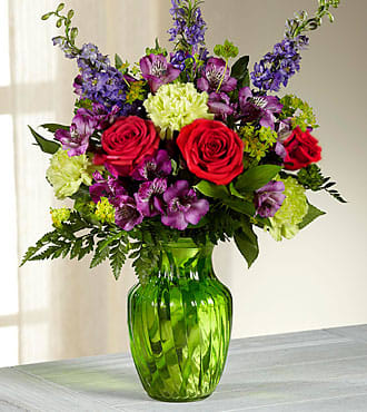Green Acres - Showcasing a fresh-from-the-garden appeal that will captivate everyone with its graceful beauty, this fresh flower arrangement is ready to create a special moment they will never forget. Red roses draw them in, surrounded by the alluring textures of green carnations, purple larkspur, purple Peruvian Lilies, bupleurum, and a variety of fresh greens. Vases may vary depending on stock availability.